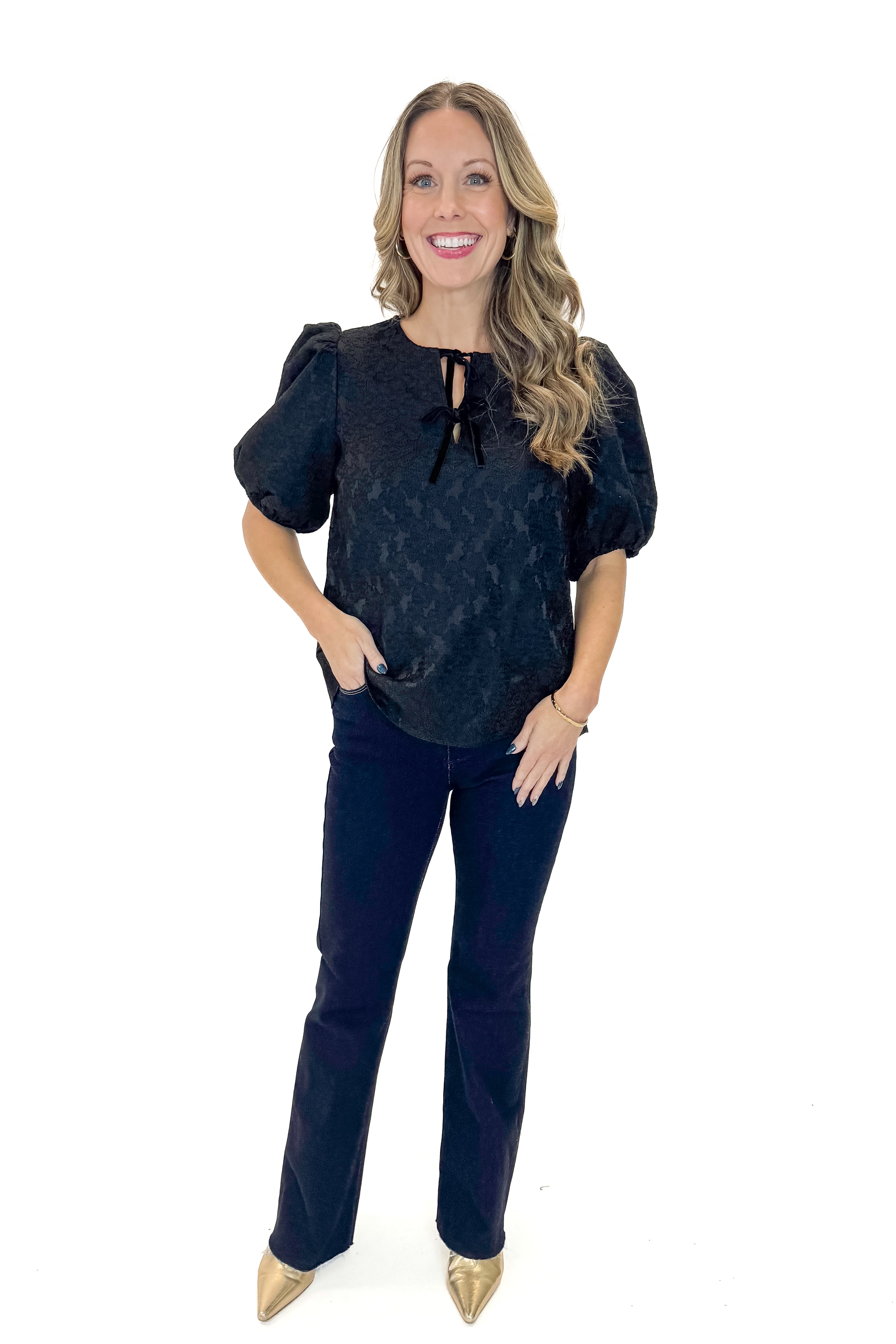 Front view of woman wearing Black Lace Ren Top with jeans against white studio background.