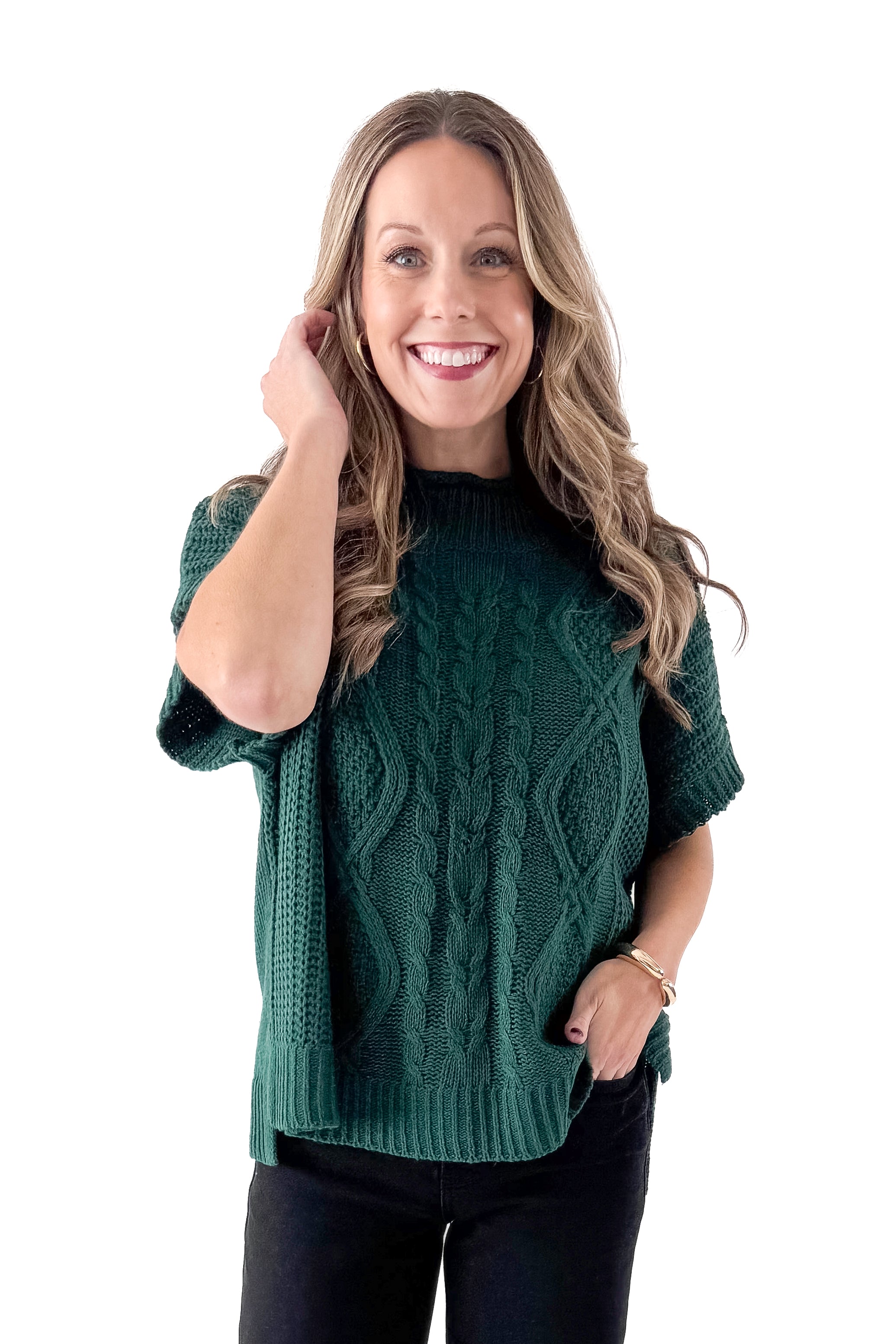Front view of woman wearing Green Claude Cable Knit Sweater with jeans against white studio background.