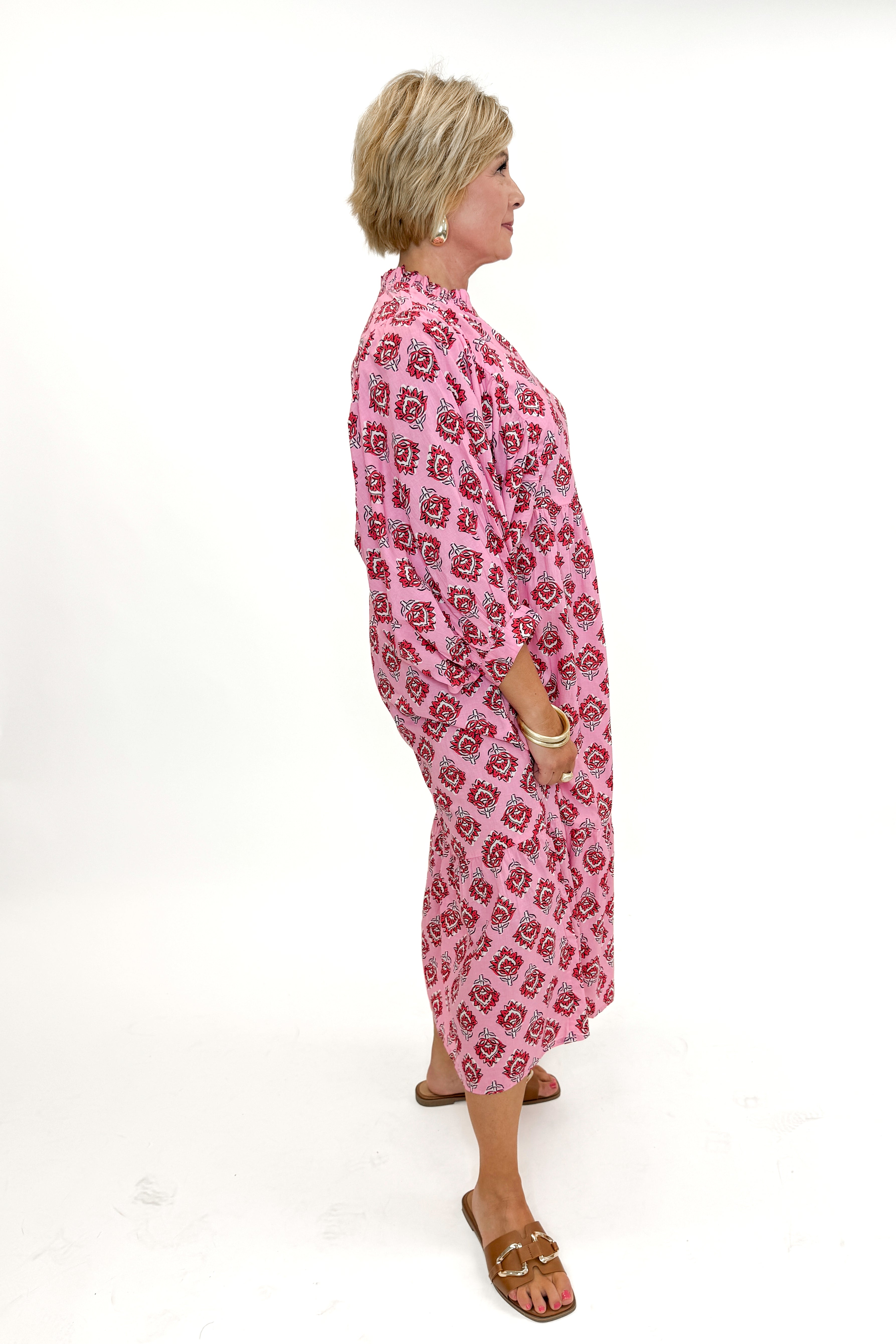 Side view of woman wearing Pink Waylon Midi Dress by MudPie against white studio background.