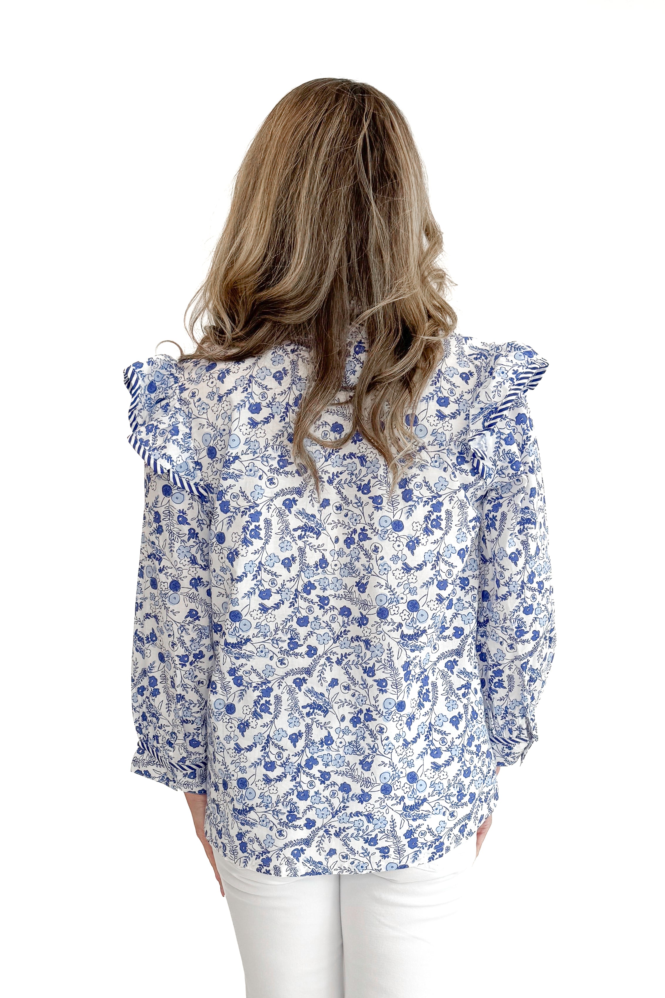 Back view of woman wearing Blue Beaufort Floral 3/4 Sleeve Top by MudPie with white jeans against white studio background.