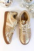 Pair of gold sneakers with decorative patterns on a white background with disco balls.