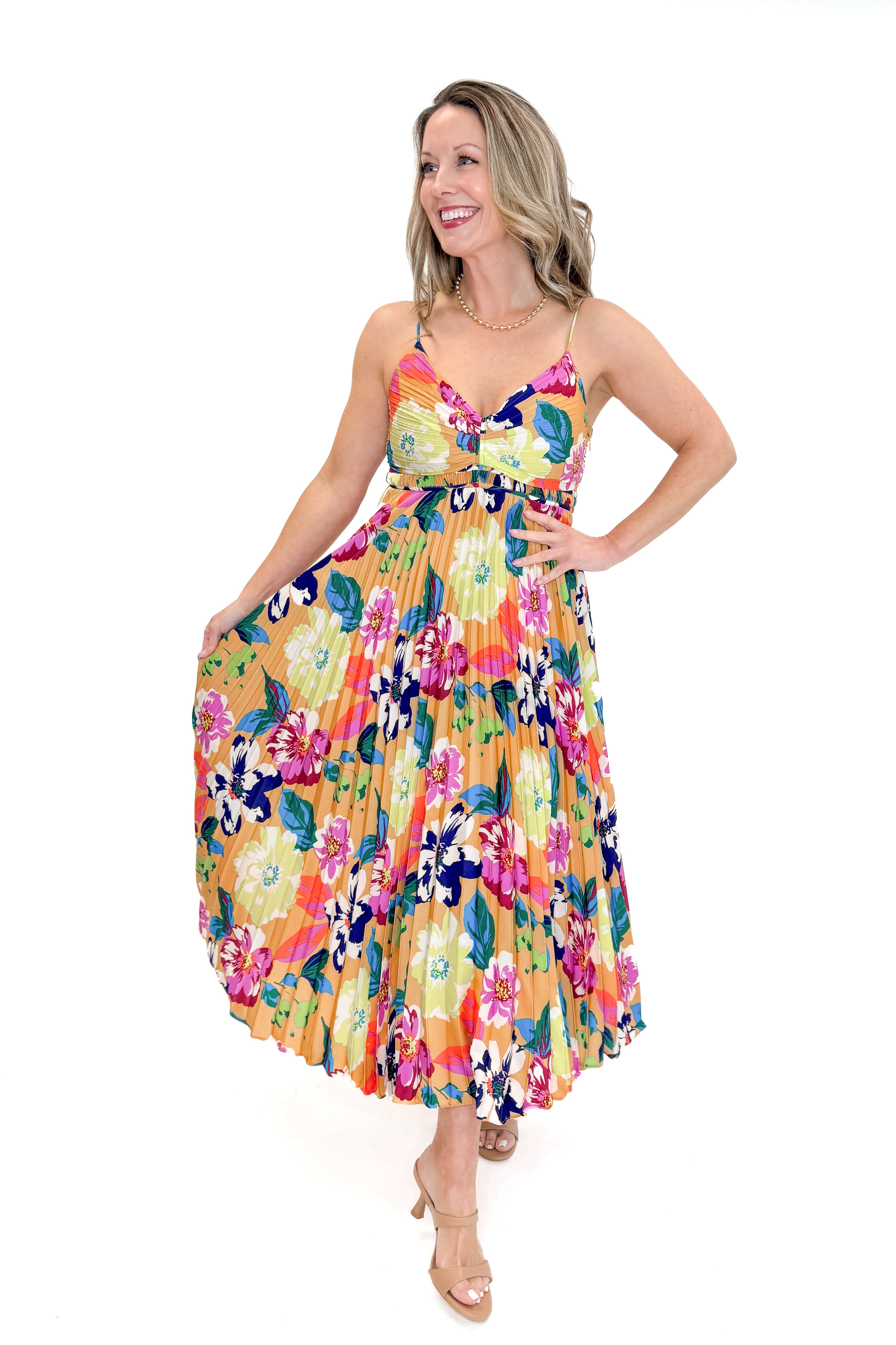 Front view of woman wearing Taupe & Multi Floral Print Pleated Midi Dress by Skies Are Blue against white studio background.