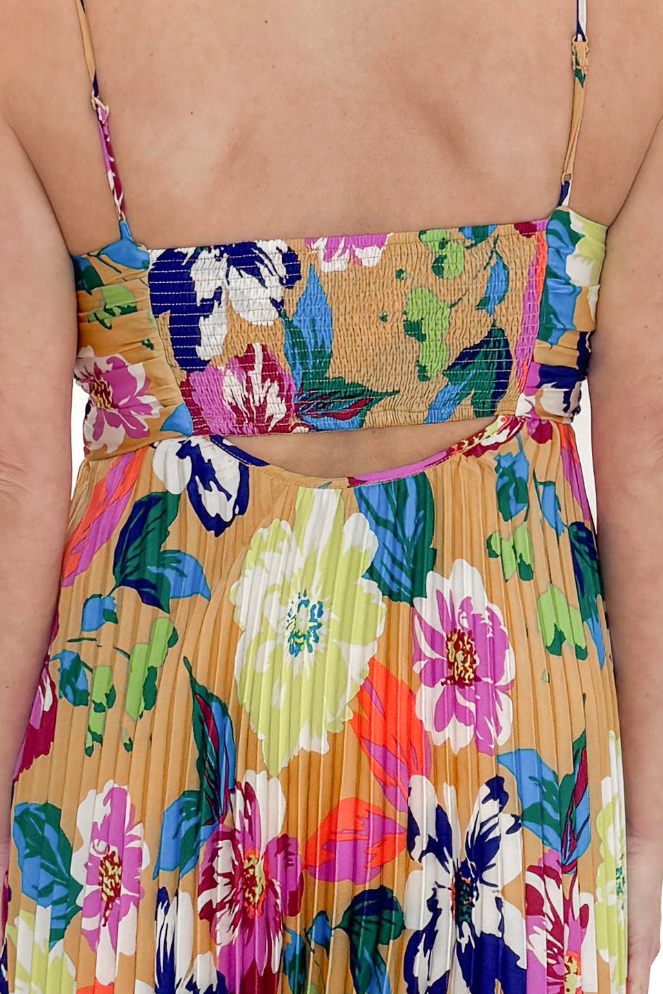 Back detail view of woman wearing Taupe & Multi Floral Print Pleated Midi Dress by Skies Are Blue against white studio background.