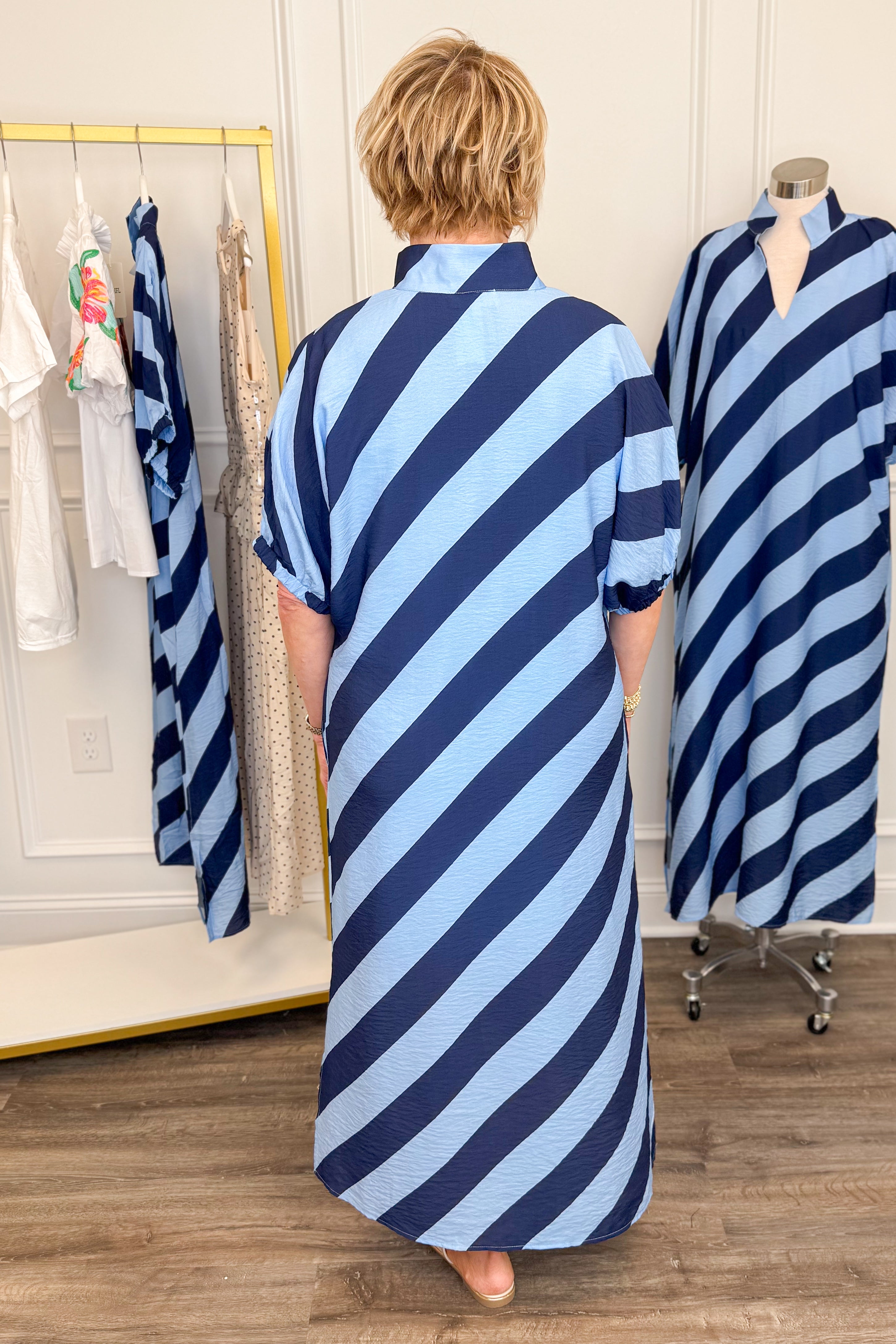 Back view of woman wearing Navy & Light Blue Diagonal Striped Midi Dress by Entro with gold sandals.