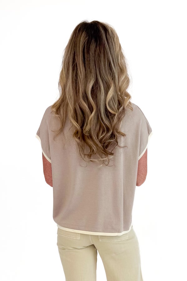 Woman wearing a sheer beige top and light-colored pants on a white background