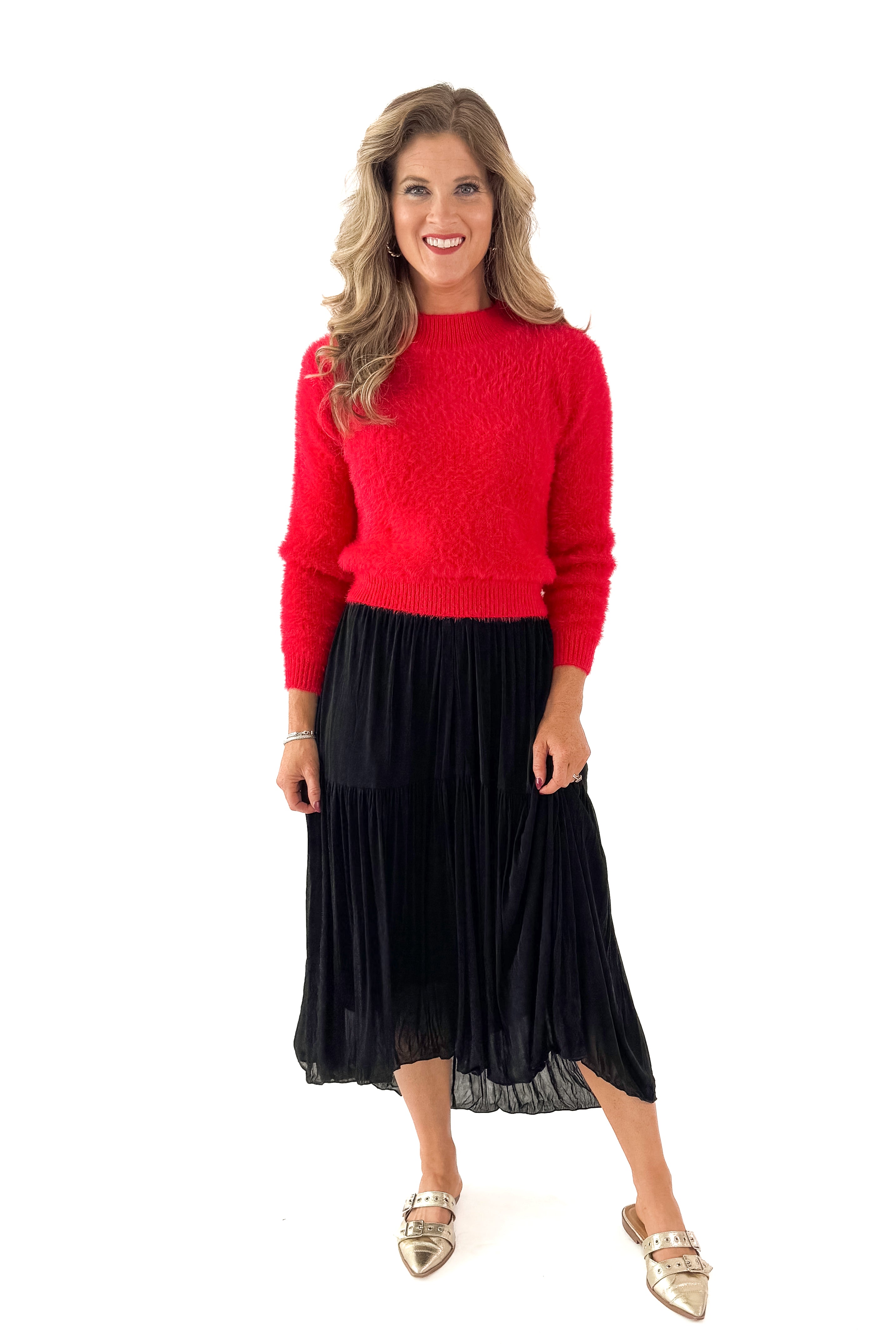 Front view of woman wearing red sweater with black skirt against white studio background.