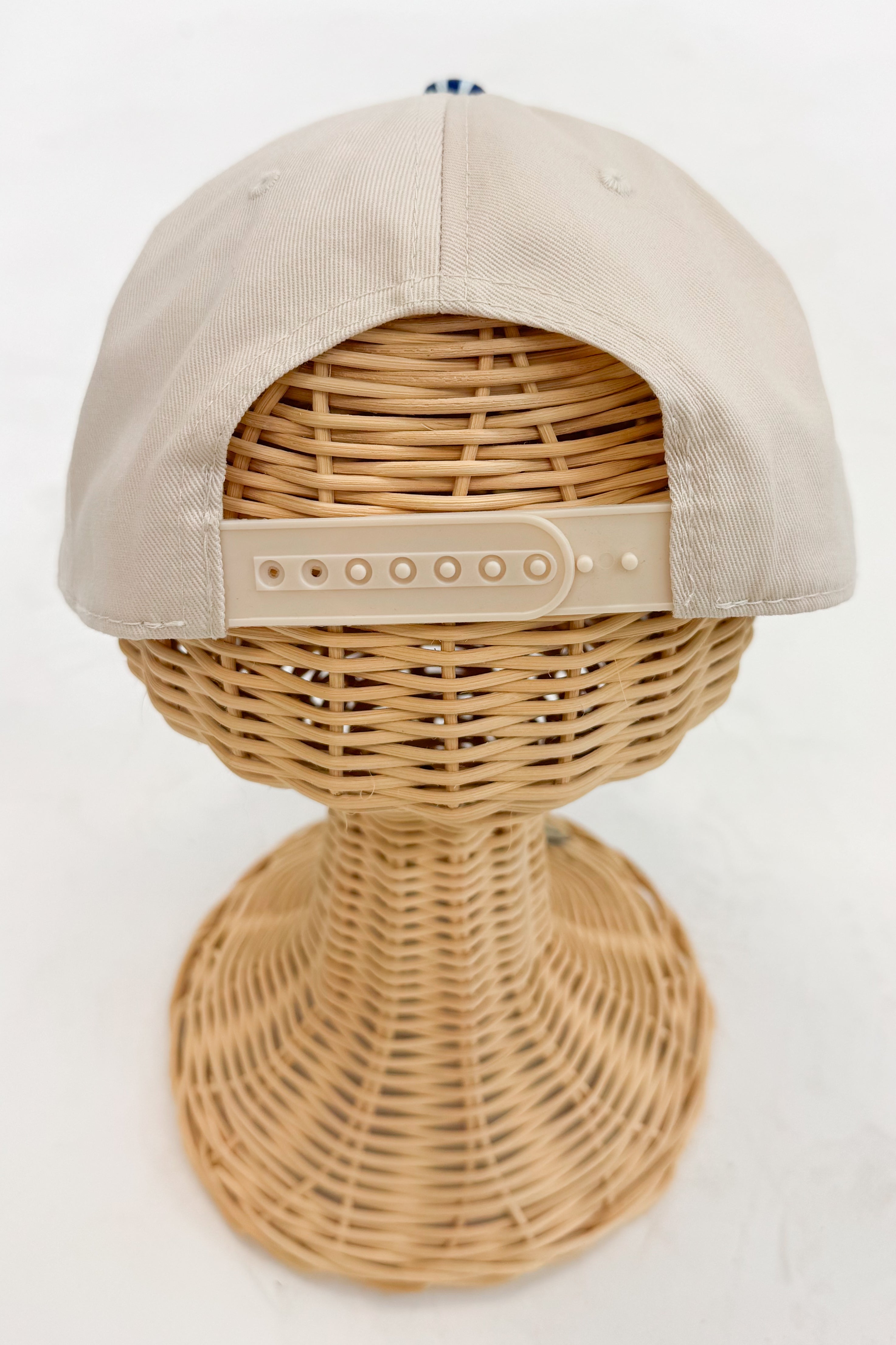 Back view of the striped-brim baseball cap featuring an adjustable strap closure.