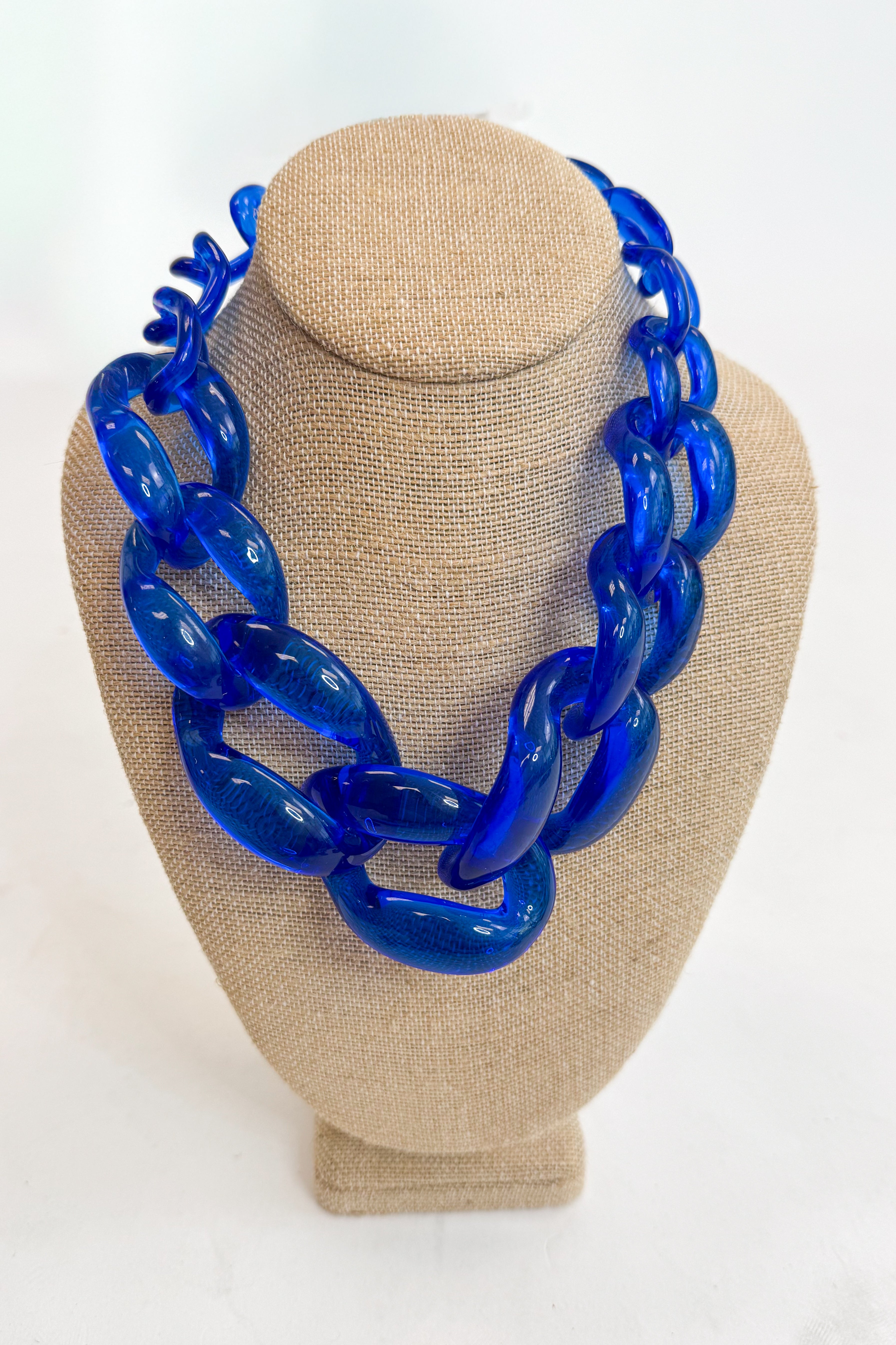 Blue chain necklace on a beige mannequin bust against a white background
