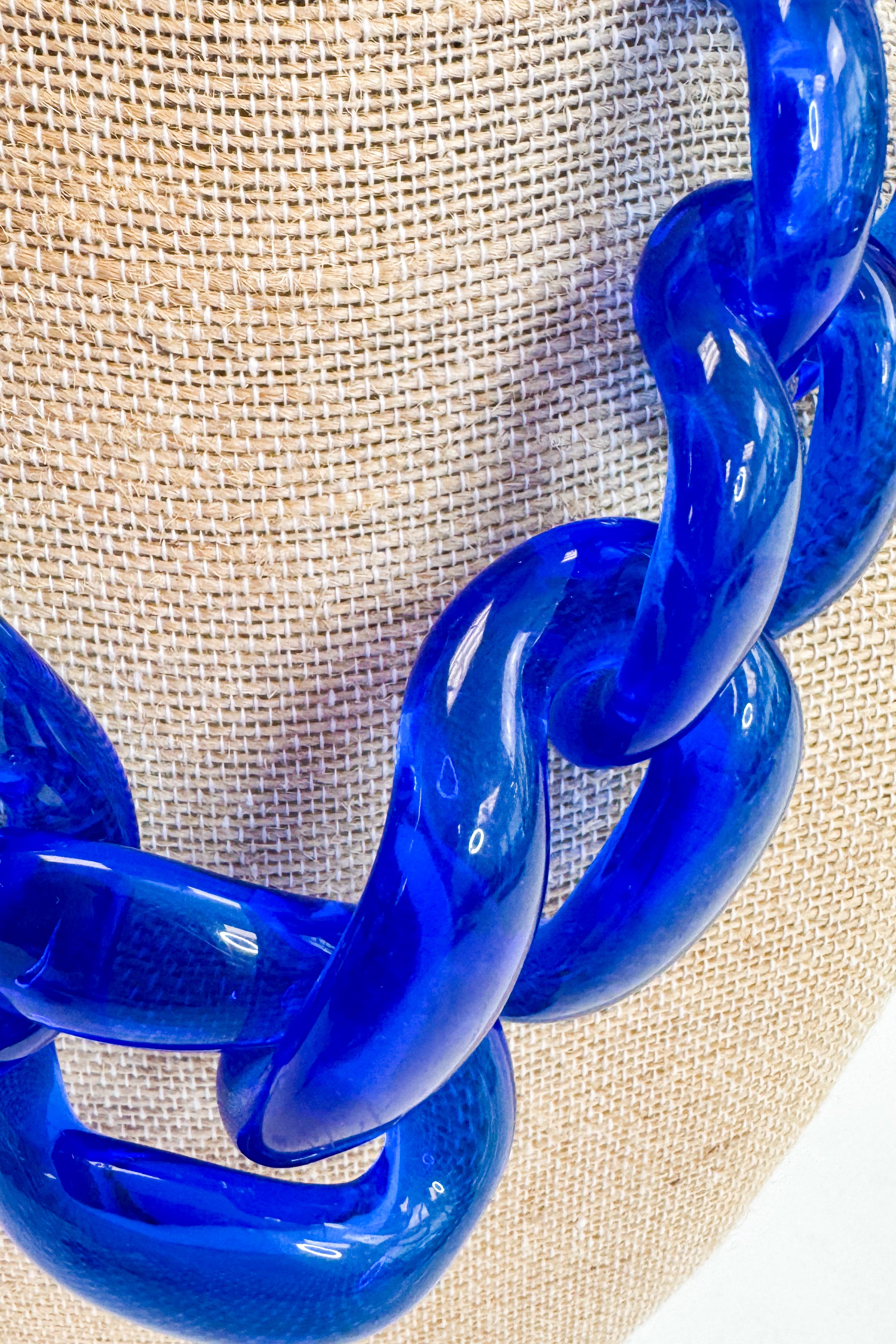Blue chain necklace on a beige fabric background