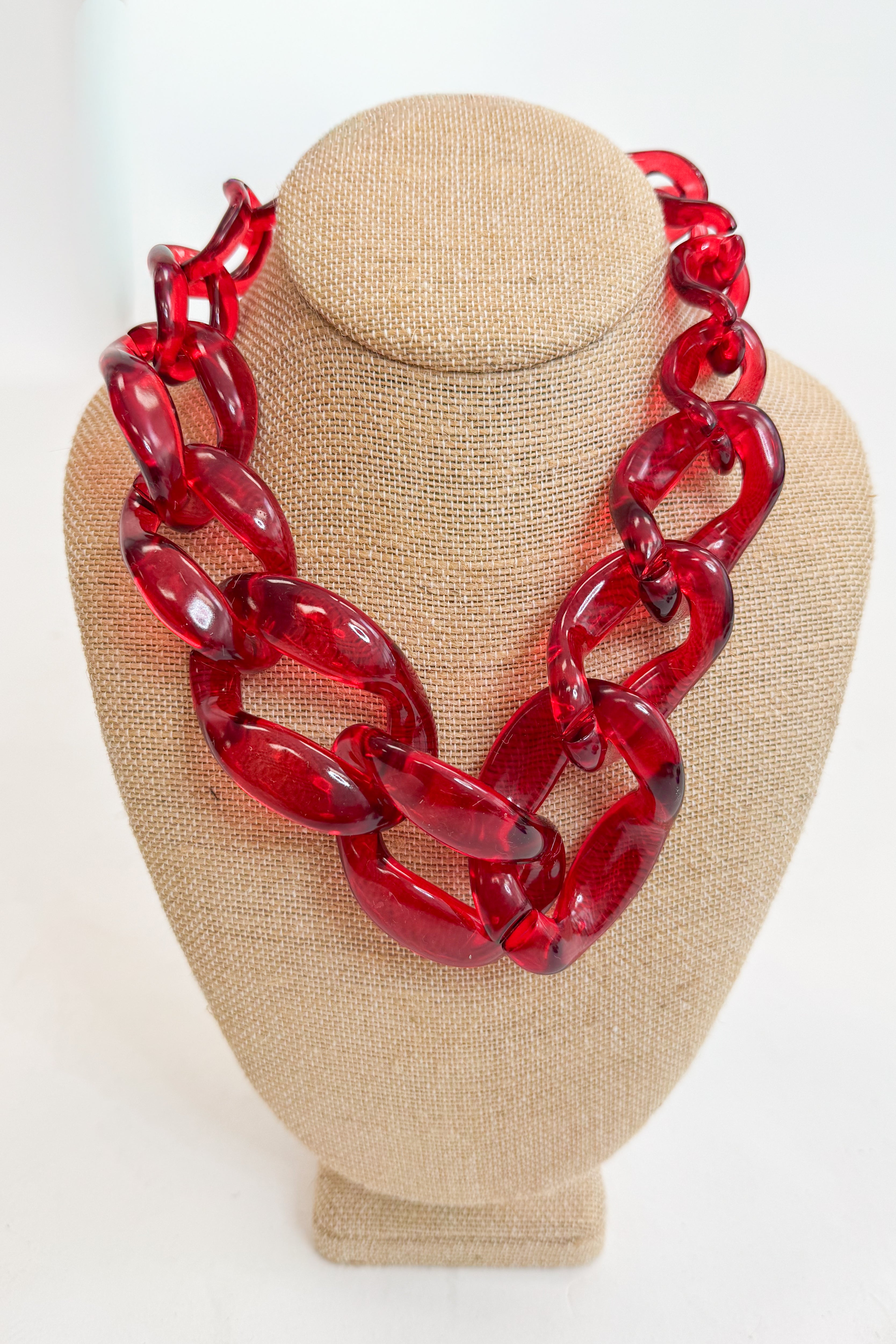 Red chain necklace on a beige mannequin bust against a white background