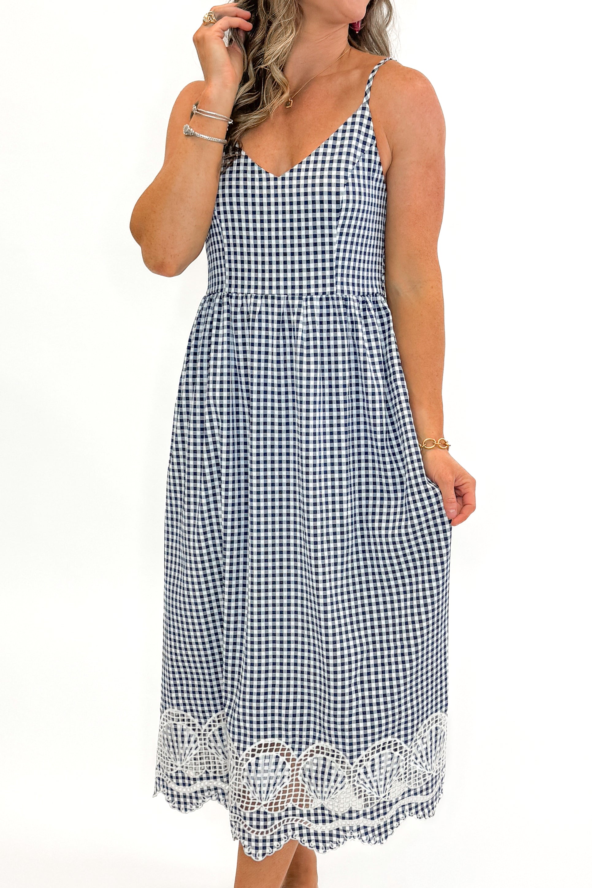 Front view of woman wearing Navy Gingham With Shell Embroidery Dress with sandals against white studio background.