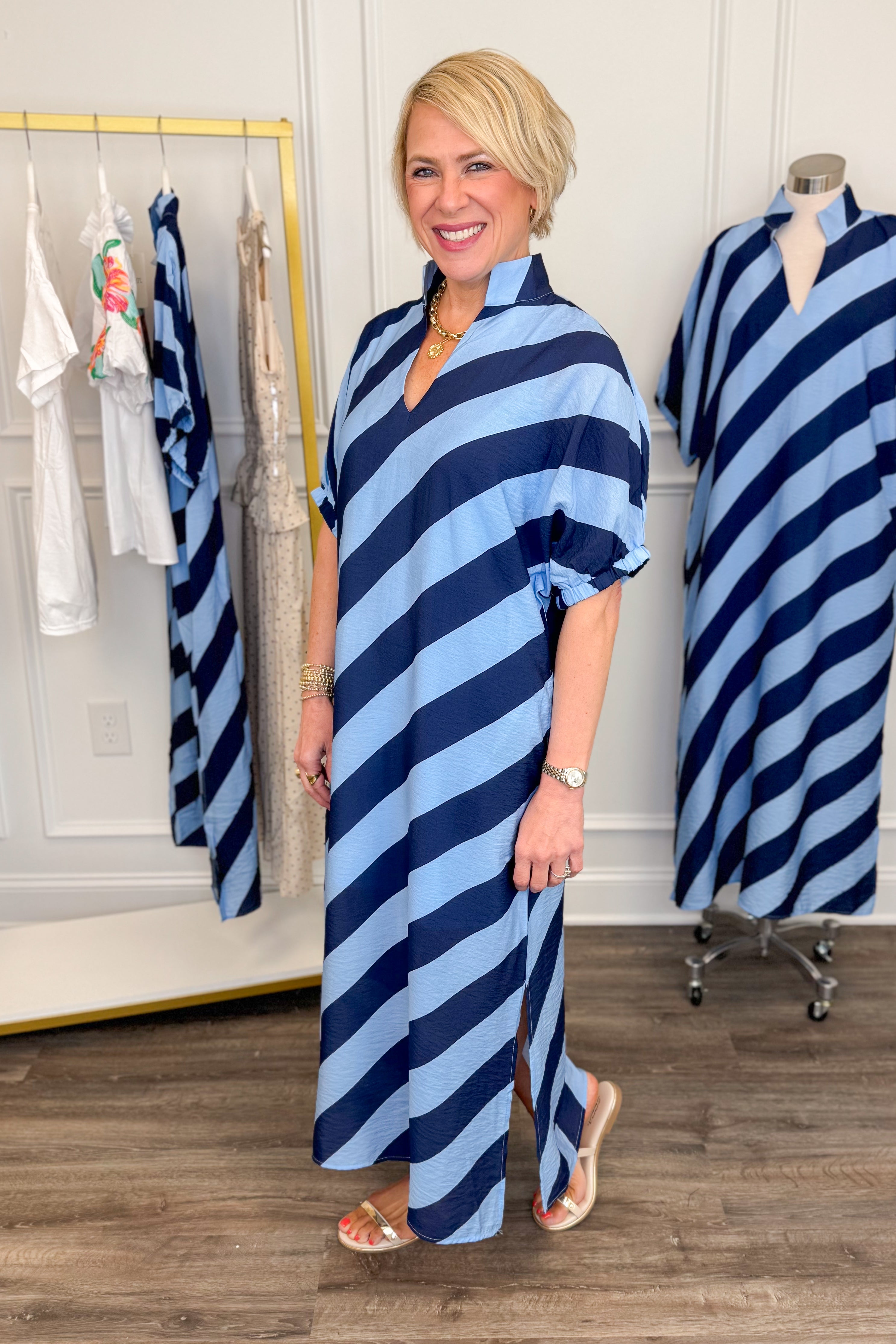Side view of woman wearing Navy & Light Blue Diagonal Striped Midi Dress by Entro with gold sandals.