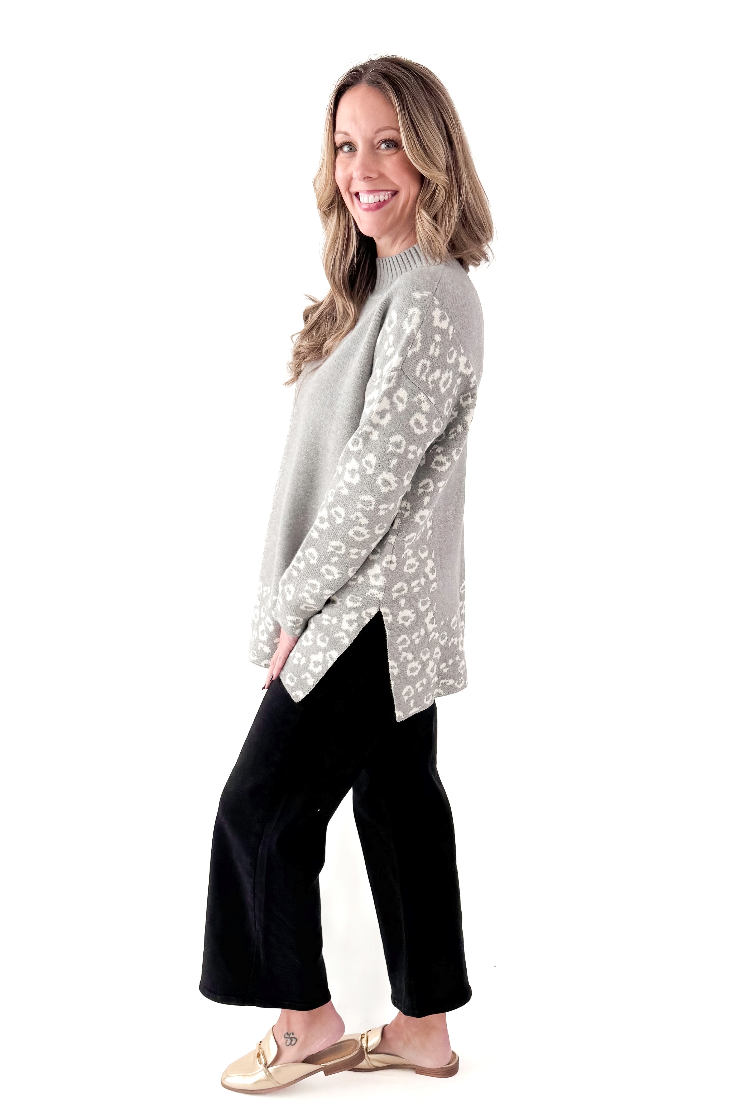 Side view of woman wearing Grey Leopard Print Lined Sweater with jeans against white studio background.