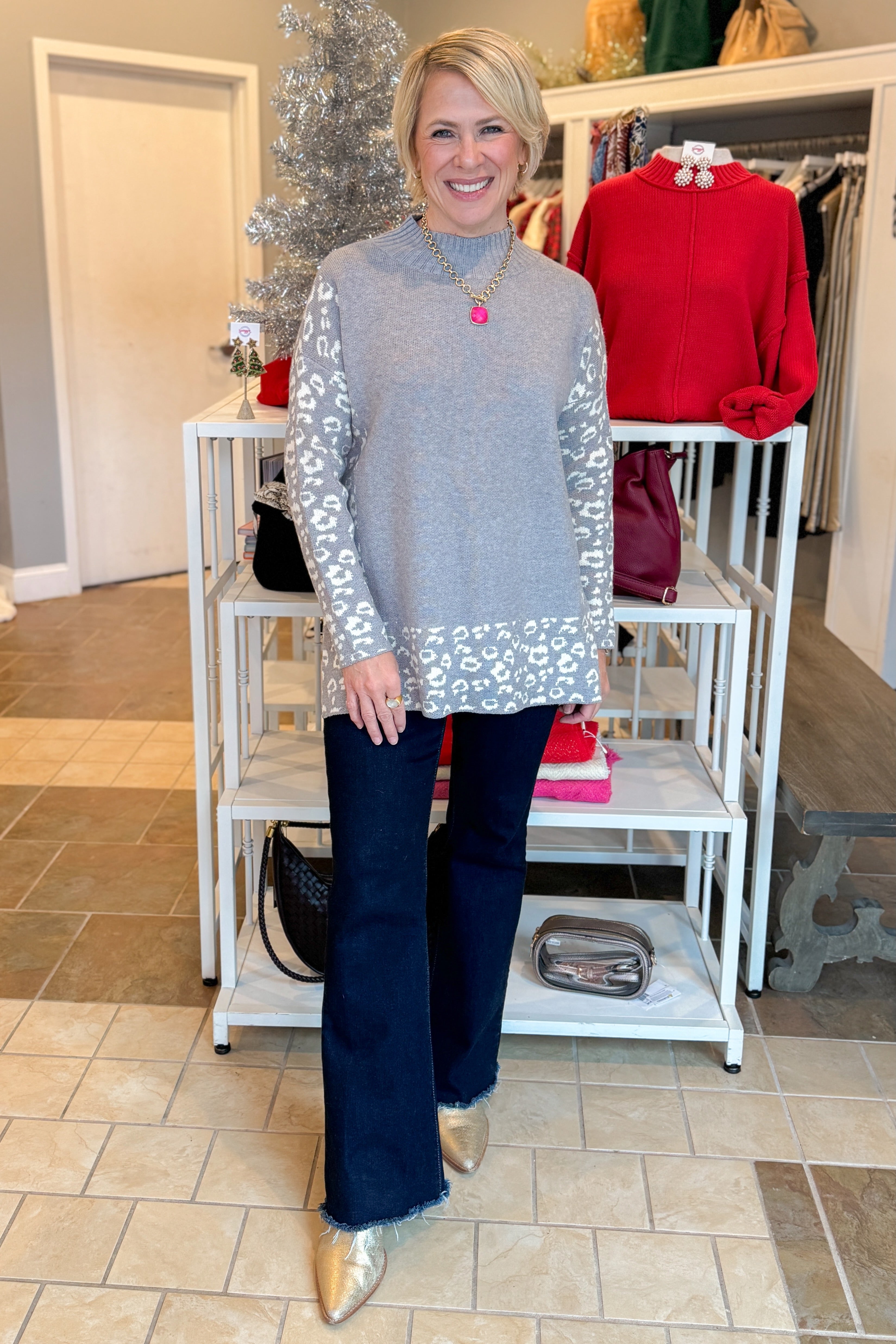 Front view of woman wearing Grey Leopard Print Lined Sweater with jeans at a boutique.