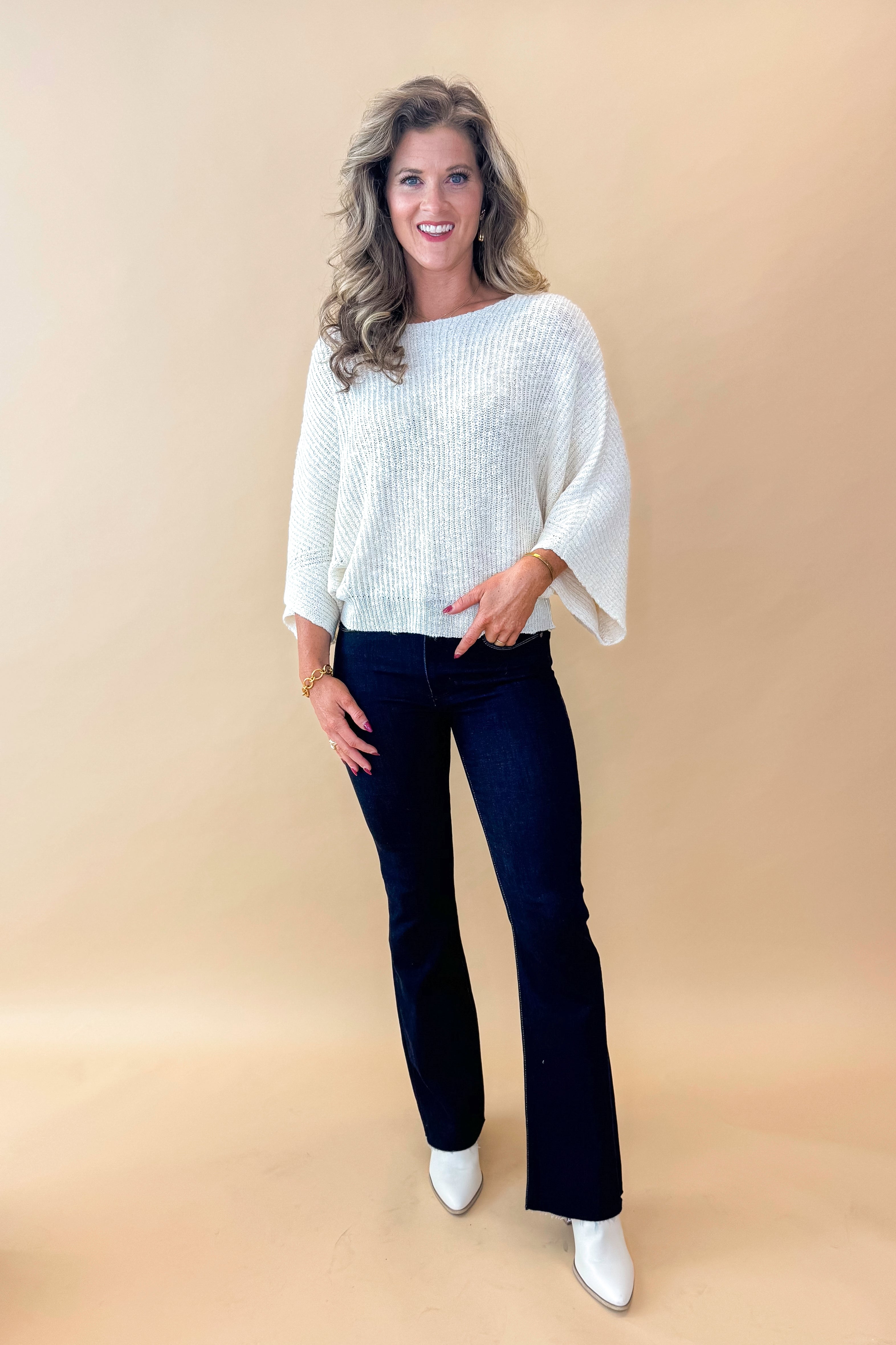 Front view of model wearing top with Super Dark Wash Flare Jeans against tan studio background.