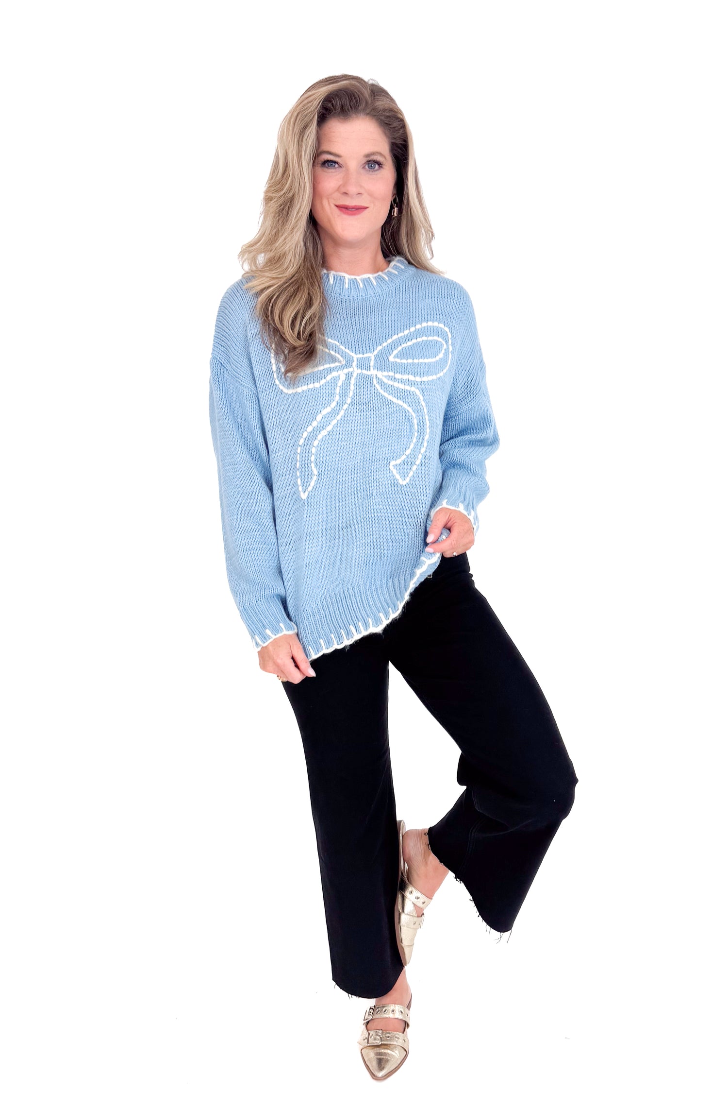 Woman wearing a light blue sweater with a large bow design on a white background