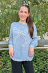 Woman wearing a blue sweater with a bow design outdoors