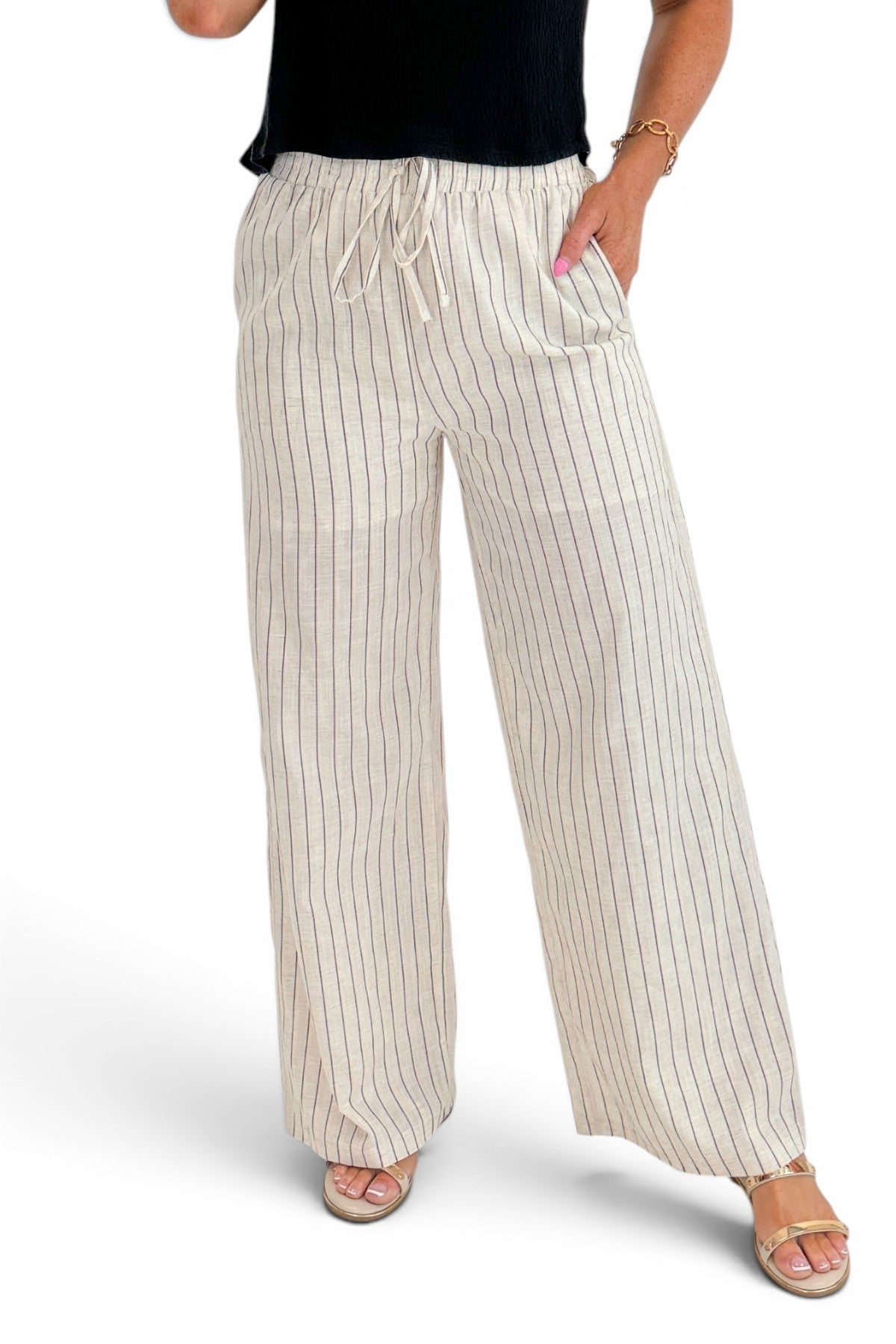 Front detail view of woman wearing Swagger Boutiqueβs Beige Striped Wide Leg Linen Pants with top against white studio background.