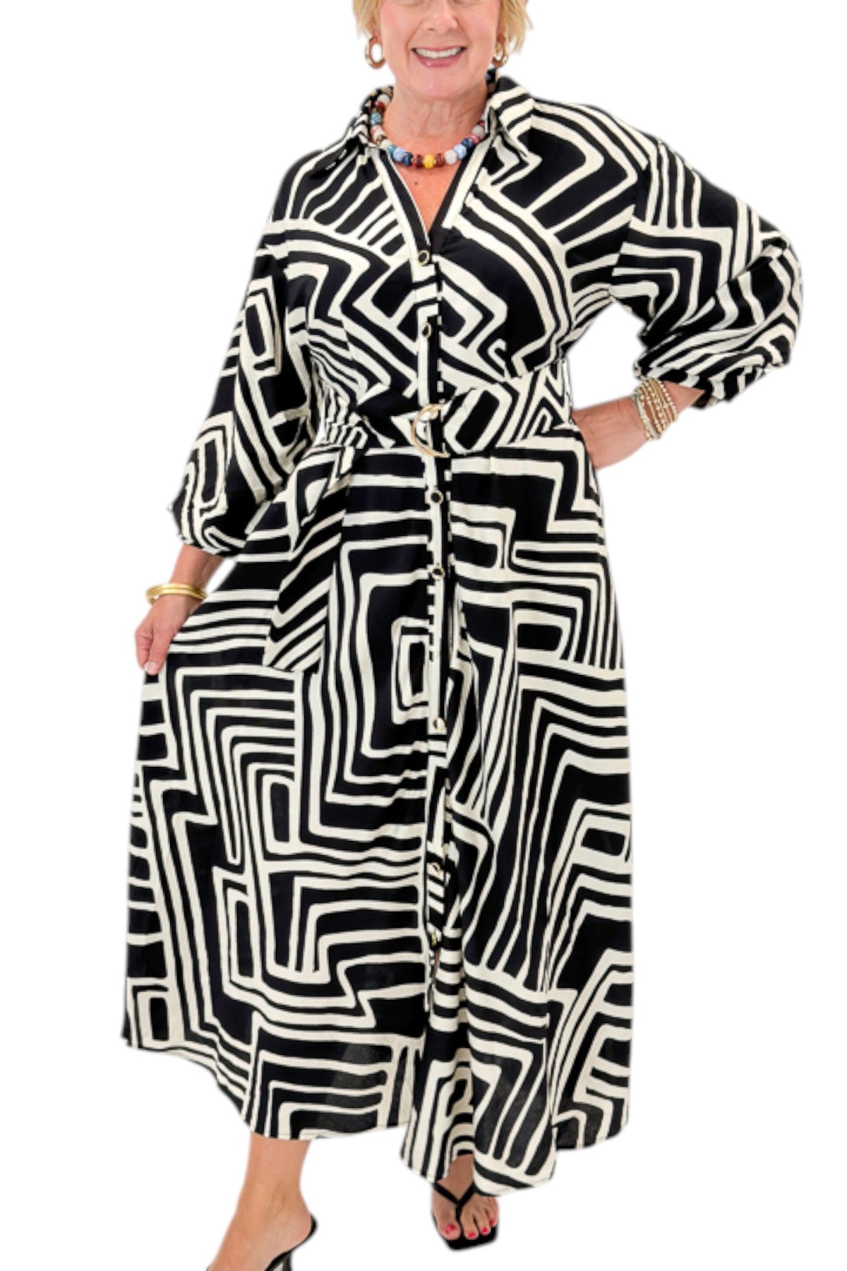 Front detail view of woman wearing Swagger Boutiqueās Black Abstract Print Midi Dress by Entro with heels against white studio background.