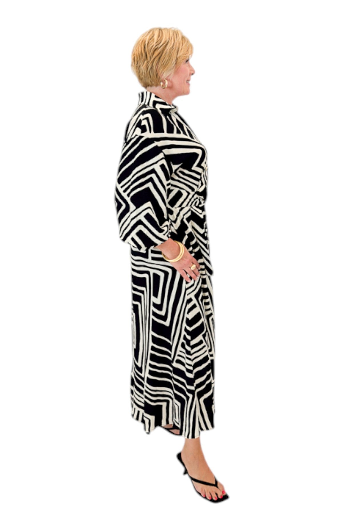 Side view of woman wearing Swagger Boutiqueās Black Abstract Print Midi Dress by Entro with heels against white studio background.