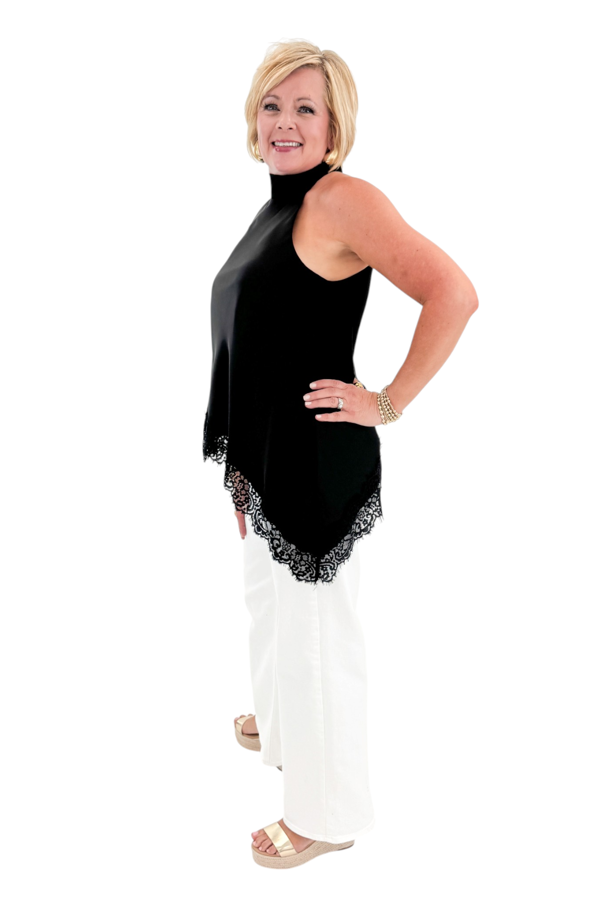 Side view of woman wearing Swagger Boutiqueβs Black Asymmetrical Halter Neck Satin Lace Top with jeans against white studio background.