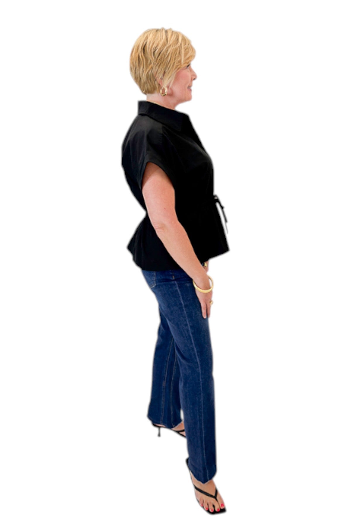 Side view of woman wearing Swagger Boutique’s Black Cinched Waist Short Sleeve Top by Entro with jeans against white studio background.