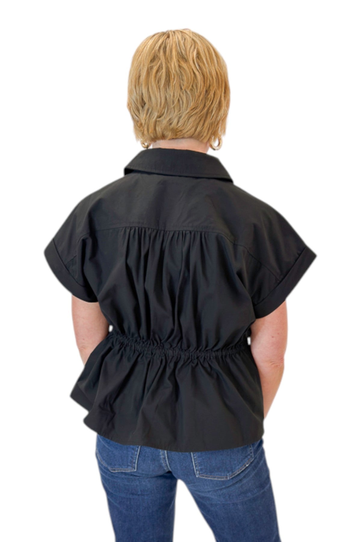 Back view of woman wearing Swagger Boutique’s Black Cinched Waist Short Sleeve Top by Entro with jeans against white studio background.
