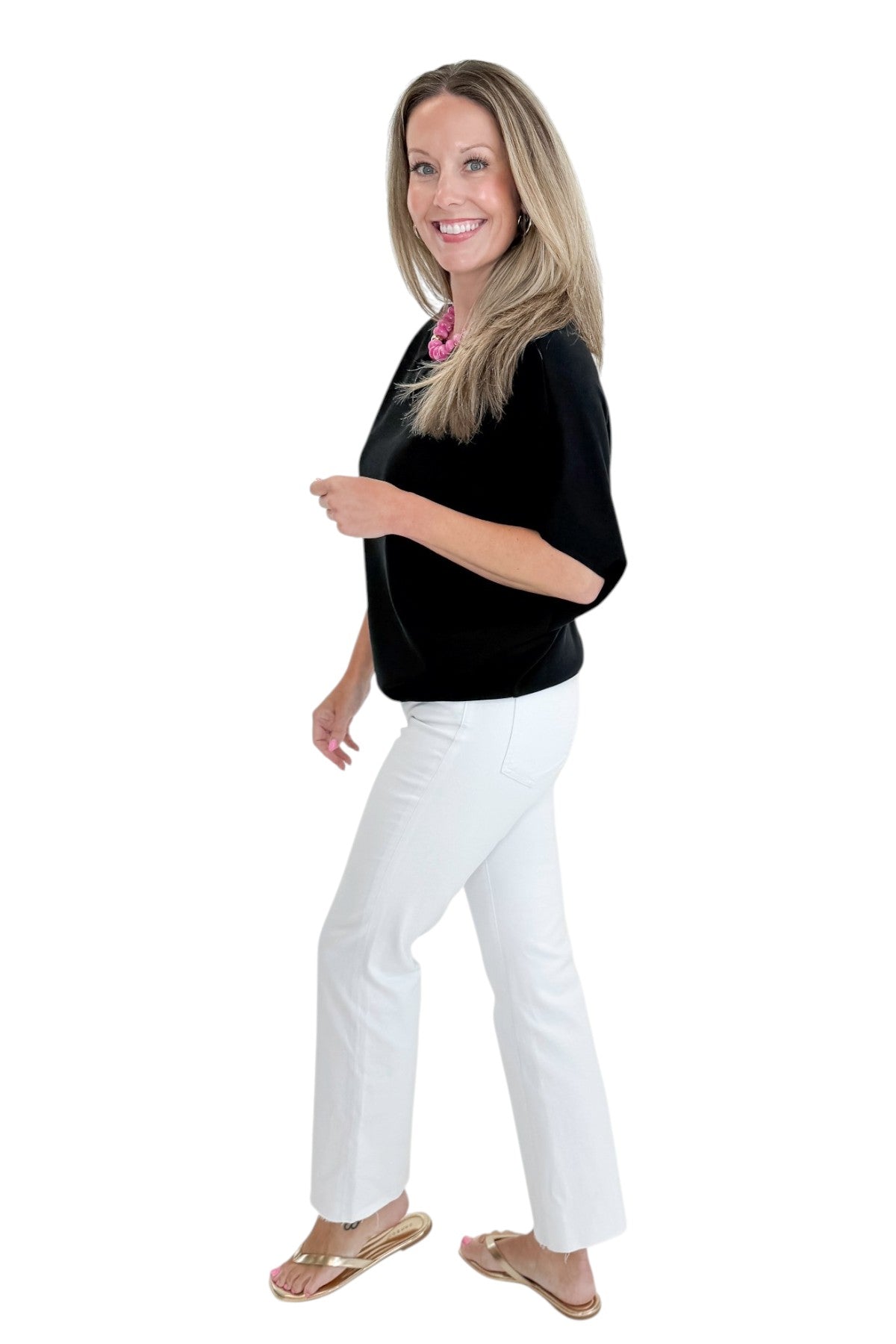 Side view of woman wearing Swagger Boutique’s Black Dolman Sleeve Top with jeans against white studio background.