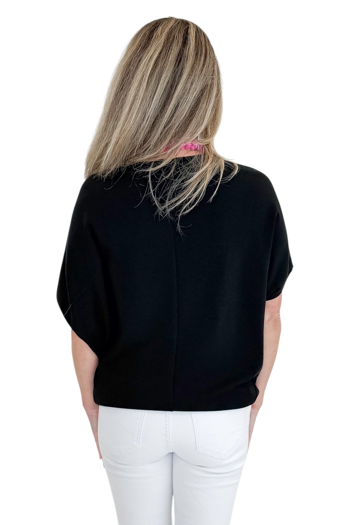 Back view of woman wearing Swagger Boutique’s Black Dolman Sleeve Top with jeans against white studio background.