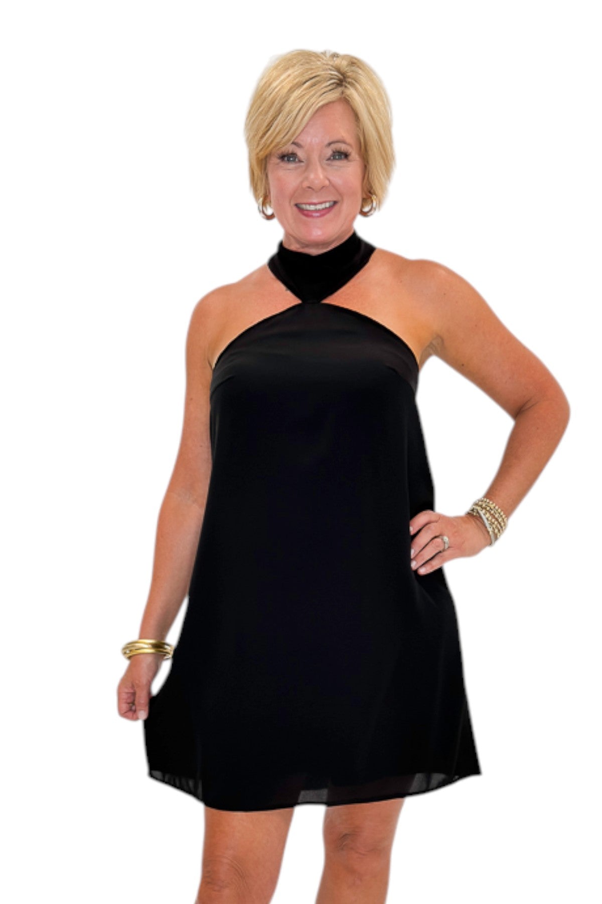 Front view of woman wearing Swagger Boutiqueās Black Halter Neck Mini Dress with heels against white studio background.