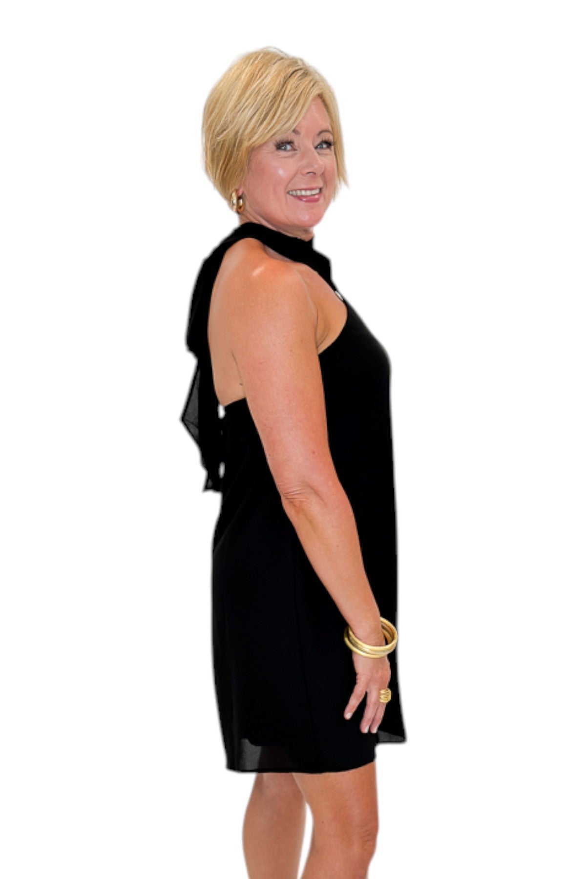 Side view of woman wearing Swagger Boutiqueās Black Halter Neck Mini Dress with heels against white studio background.