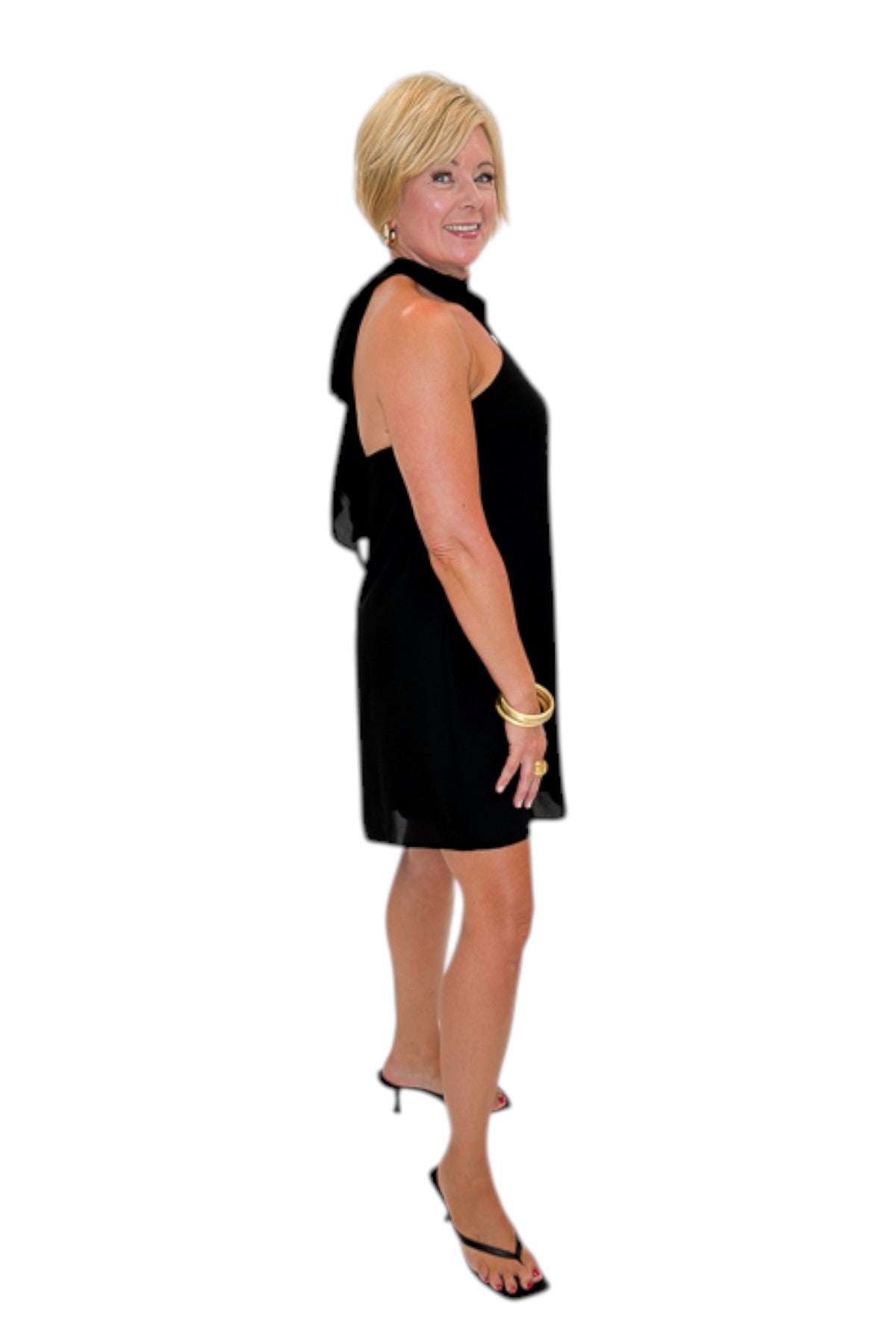 Side view of woman wearing Swagger Boutiqueās Black Halter Neck Mini Dress with heels against white studio background.