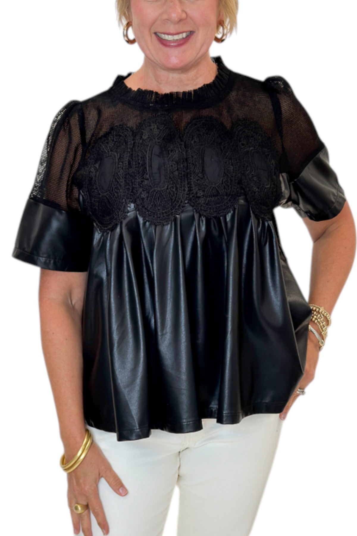 Front detail view of woman wearing Swagger Boutique’s Black Lace Applique Faux Leather Top with jeans against white studio background.