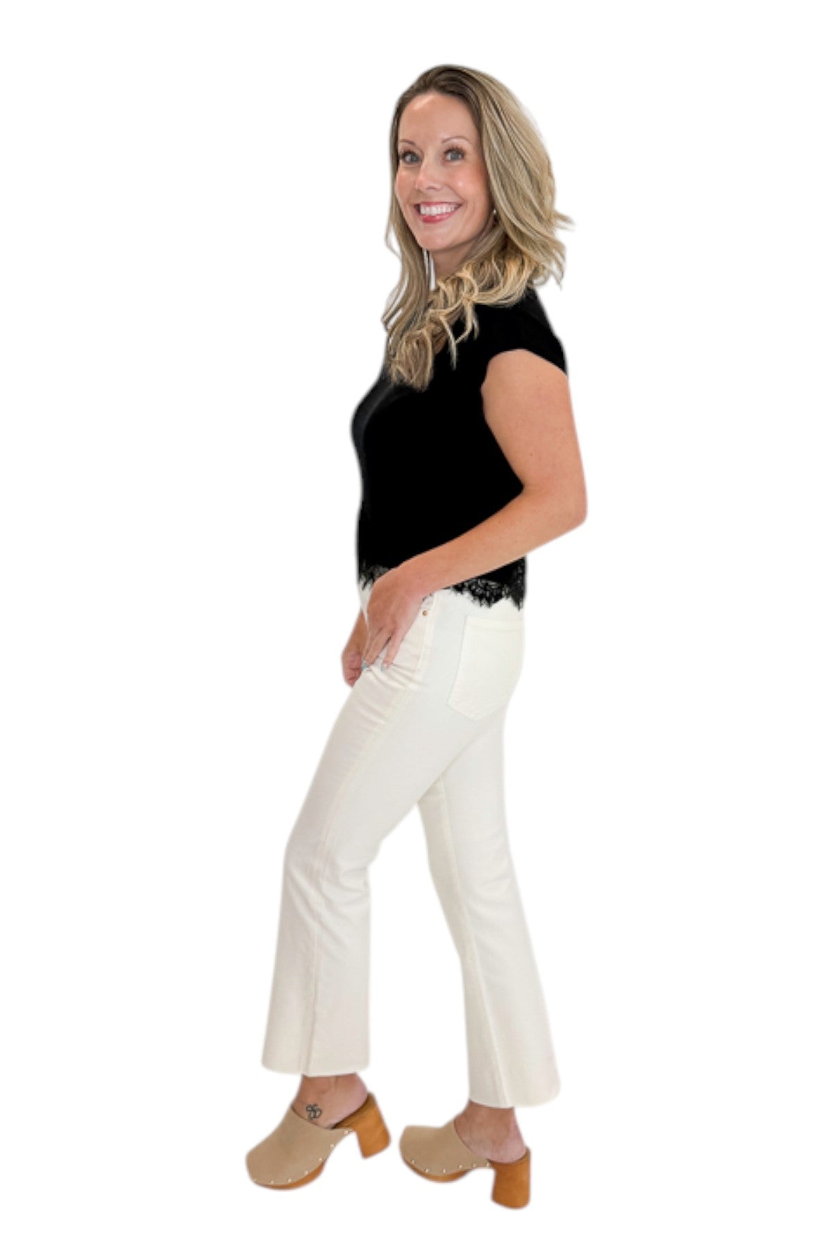 Side view of woman wearing Swagger Boutiqueās Black Short Sleeve Lace Trim Top with jeans against white studio background.