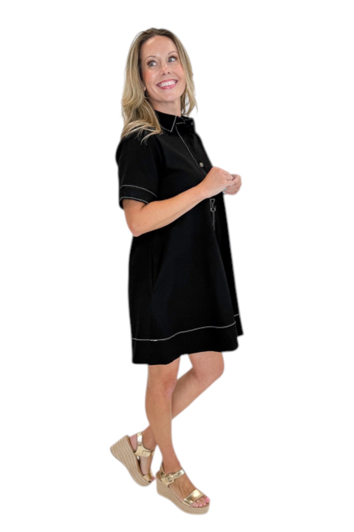 side view of woman wearing Swagger Boutiqueās Black Stitched Mini Dress with tan wedges against a white studio background.