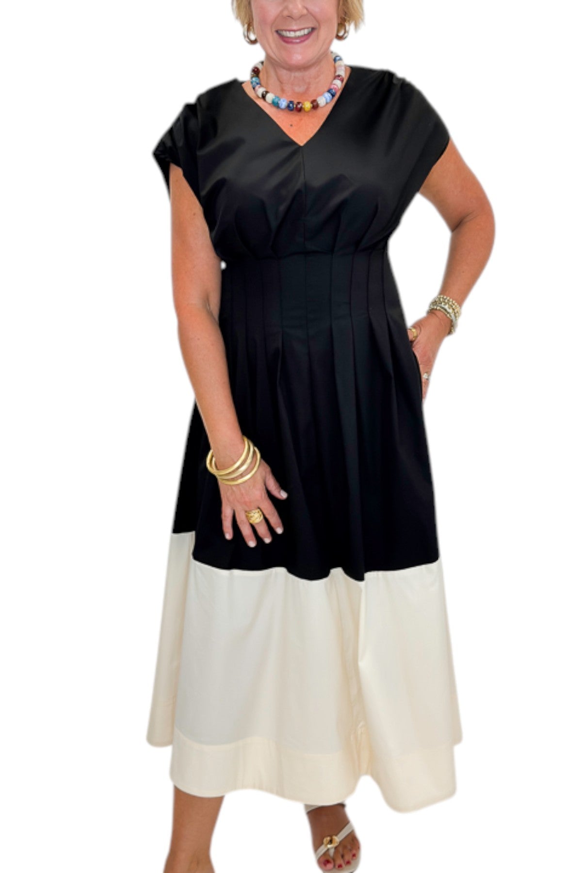 Front detail view of woman wearing Swagger Boutiqueās Black & Cream Color Block Midi Dress by Entro with sandals against white studio background.