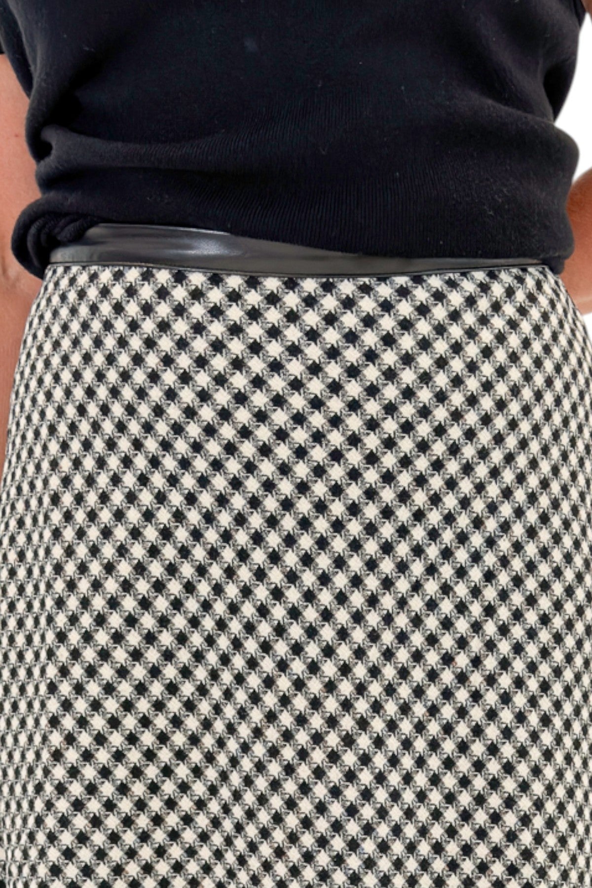 Front detail view of woman wearing Swagger Boutiqueβs Black Shirred Cap Sleeve Sweater with Black & White Plaid Midi Skirt against white studio background.