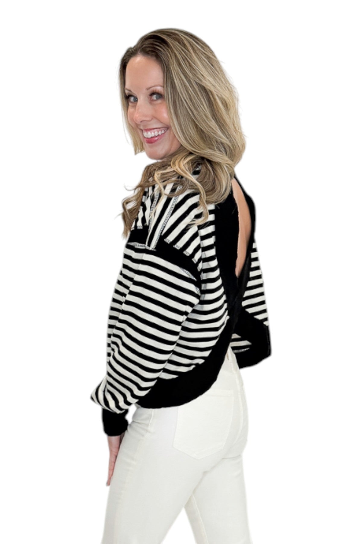 Side view of woman wearing Swagger Boutiqueās Black & White Striped Cut Out Back Sweatshirt with jeans against white studio background.