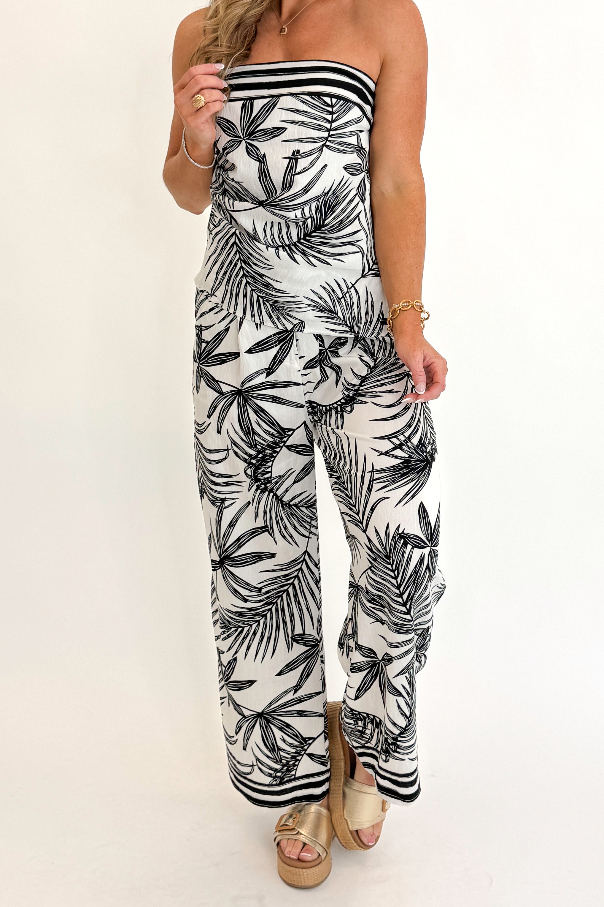 Front view of woman wearing Swagger Boutique’s Black & White Tropical Print Strapless Top with matching Black & White Tropical Print Pants against white studio background.