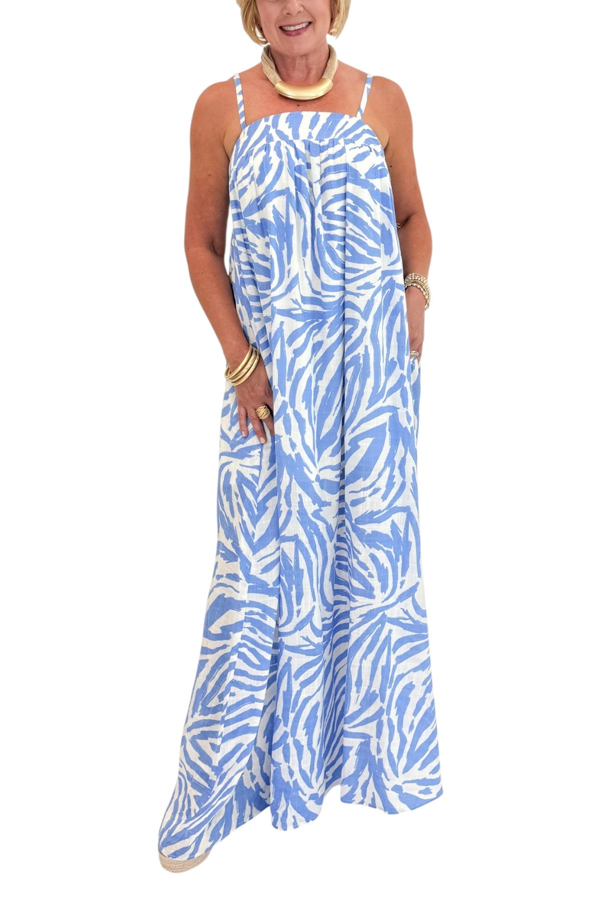 Front detail view of woman wearing Swagger Boutiqueās Blue & Cream Animal Print Maxi Dress by Entro with sandals against white studio background.