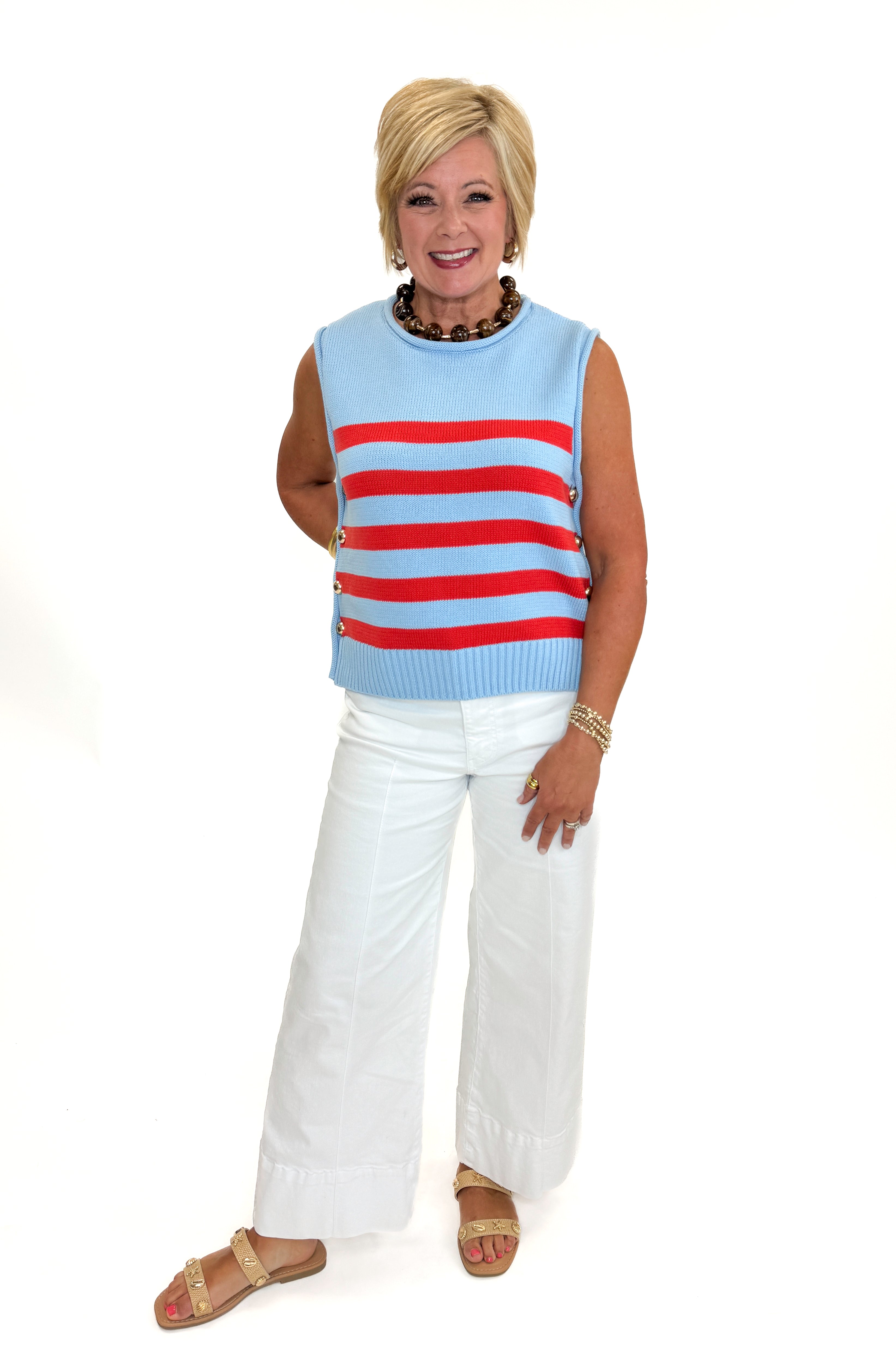 Front view of woman wearing Swagger Boutique’s Blue & Red Striped Sleeveless Sweater by Entro with jeans against white studio background.