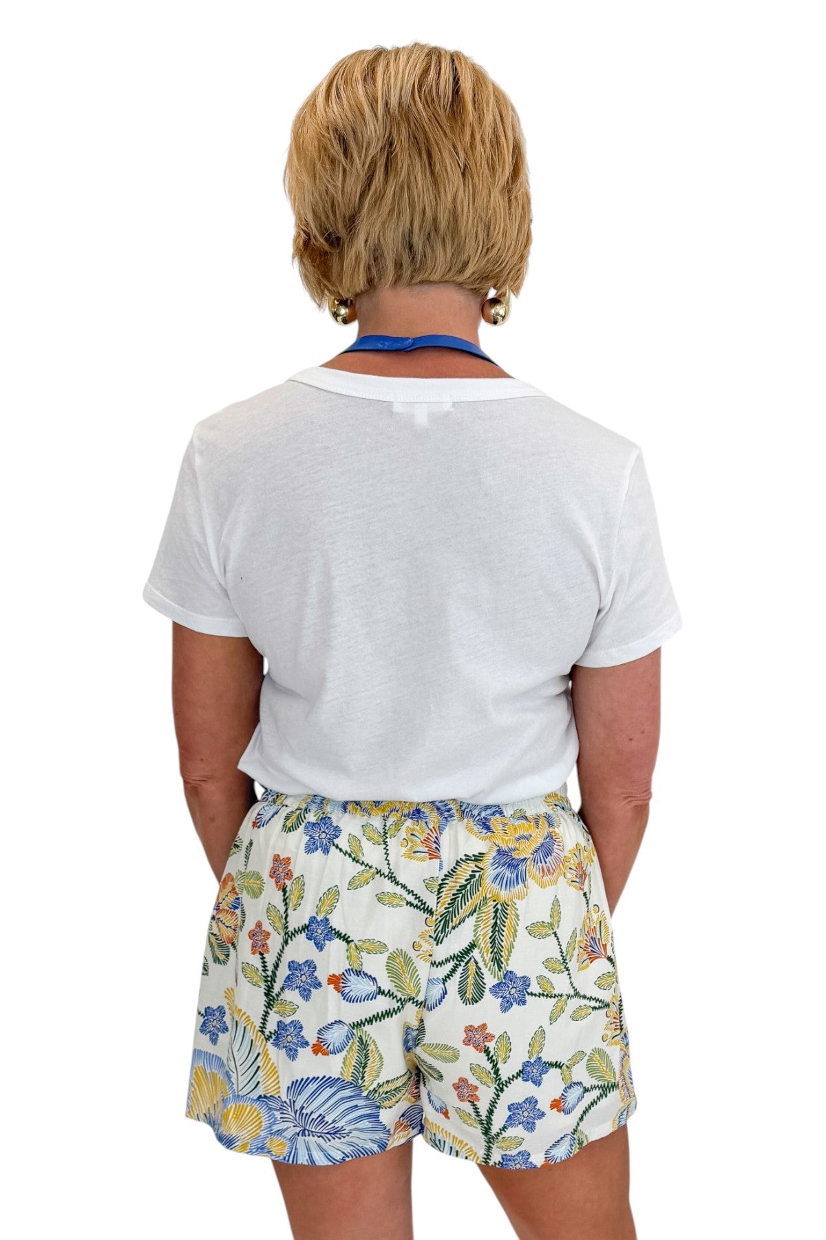 Back view of woman wearing Swagger Boutiqueās Blue & Yellow Floral Print Wrap Skort by Entro with white top against white studio background.