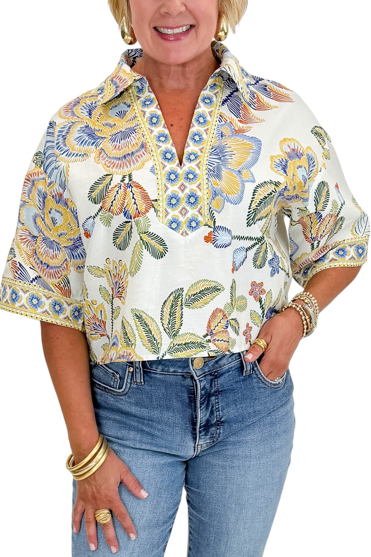 Front detail view of woman wearing Swagger Boutiqueās Blue & Yellow Floral Print Collared Top with jeans against white studio background.