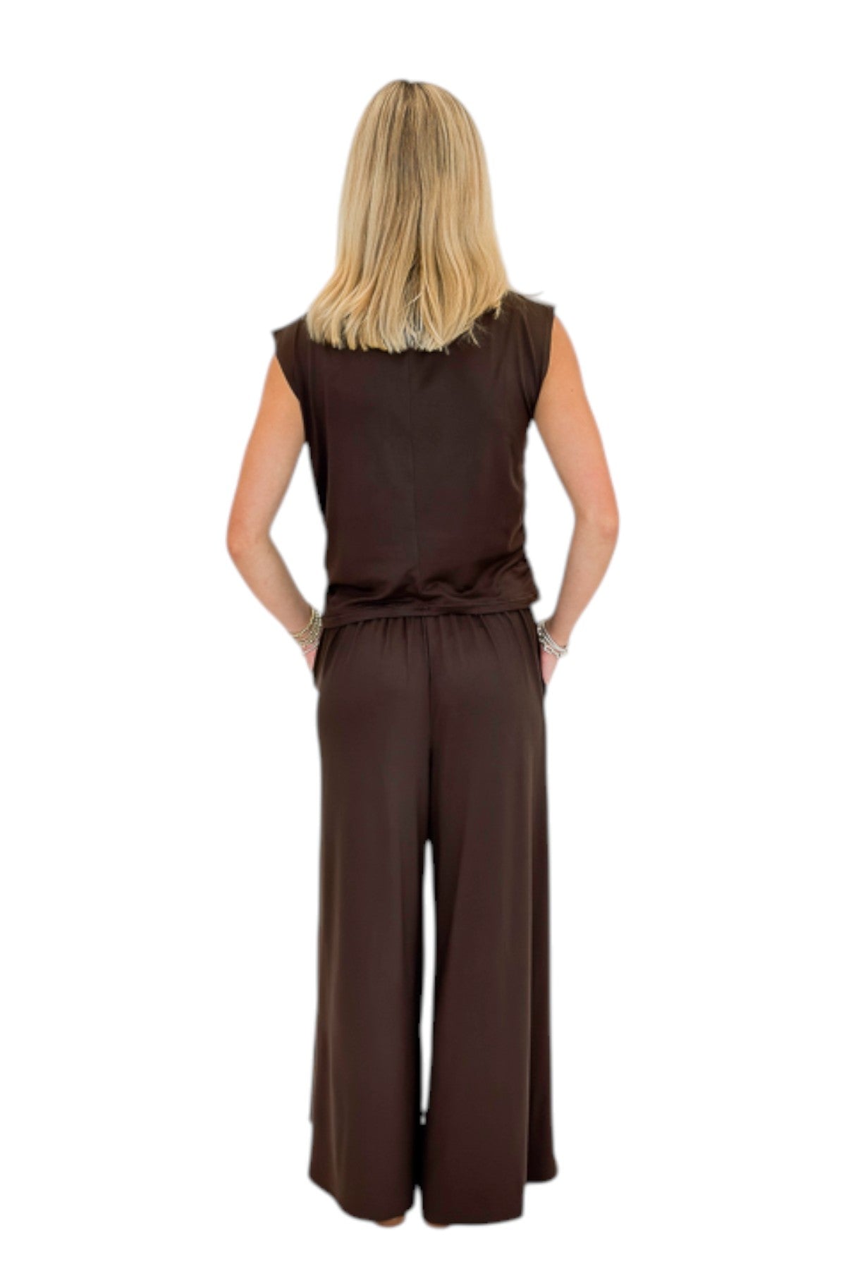 Back view of woman wearing Swagger Boutique’s Brown Pleated Wide Leg Pants with Brown Rouched Side Tank against white studio background.