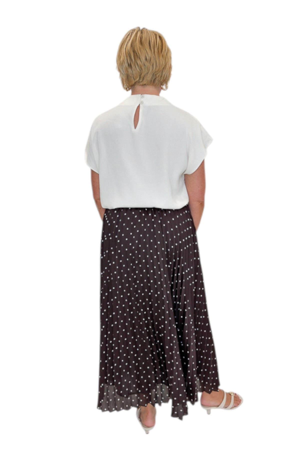 Back view of woman wearing Swagger Boutique’s Brown Polka Dot Pleated Skirt with top against white studio background.