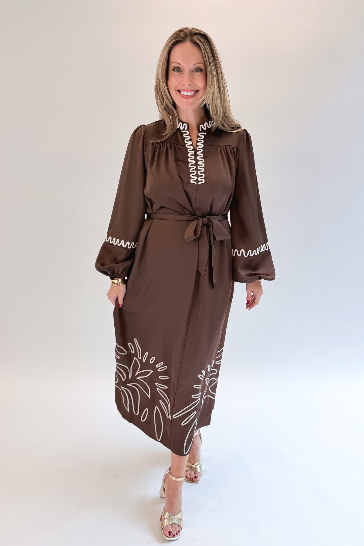 Front view of woman wearing Swagger Boutique’s Brown Satin Embroidered Midi Dress with heels against white studio background.