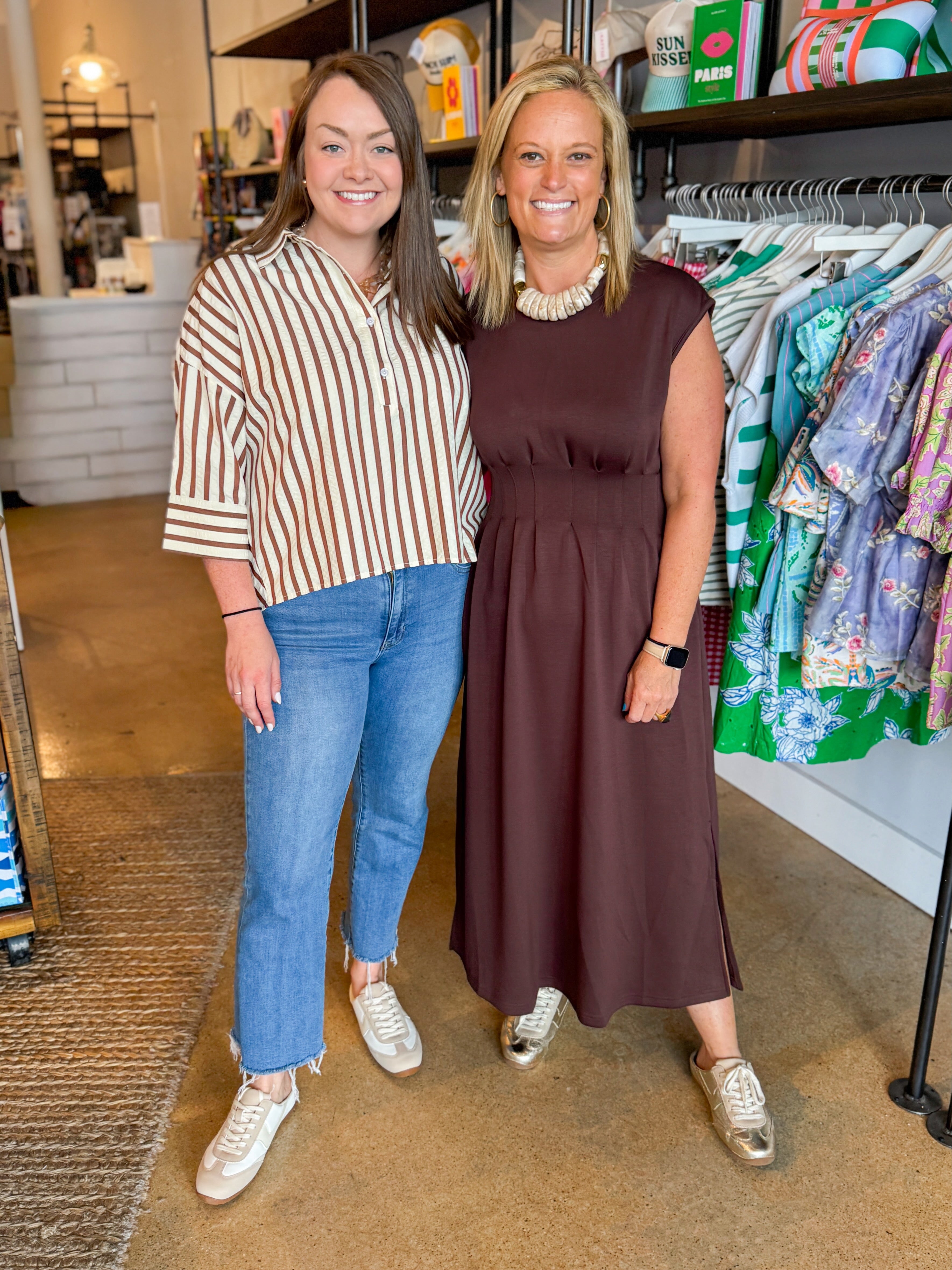 Front view of woman wearing Swagger Boutiqueās Brown Striped 3/4 Sleeve Top with jeans and woman wearing brown dress at the store.