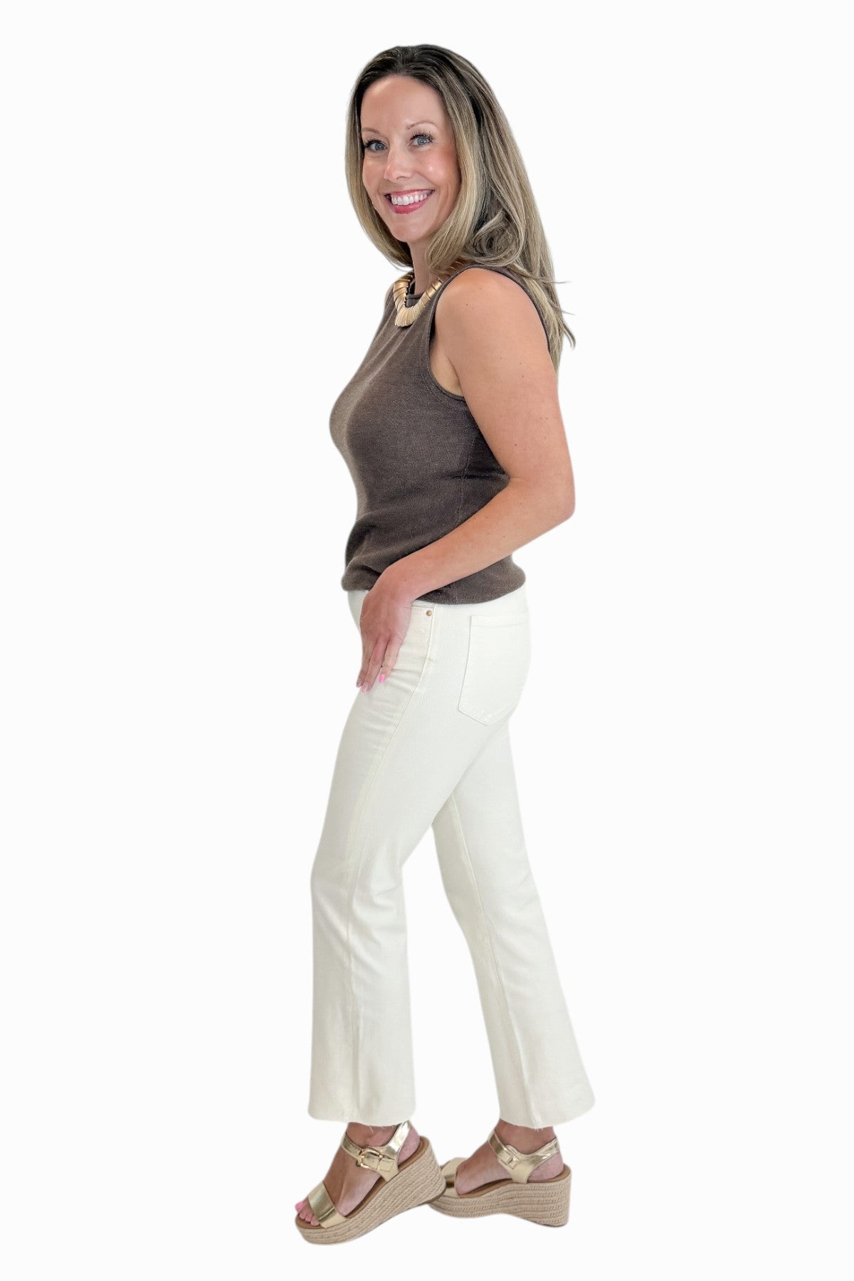 Side view of woman wearing Swagger Boutiqueās Brown Sweater Tank with Ecru jeans against white studio background.