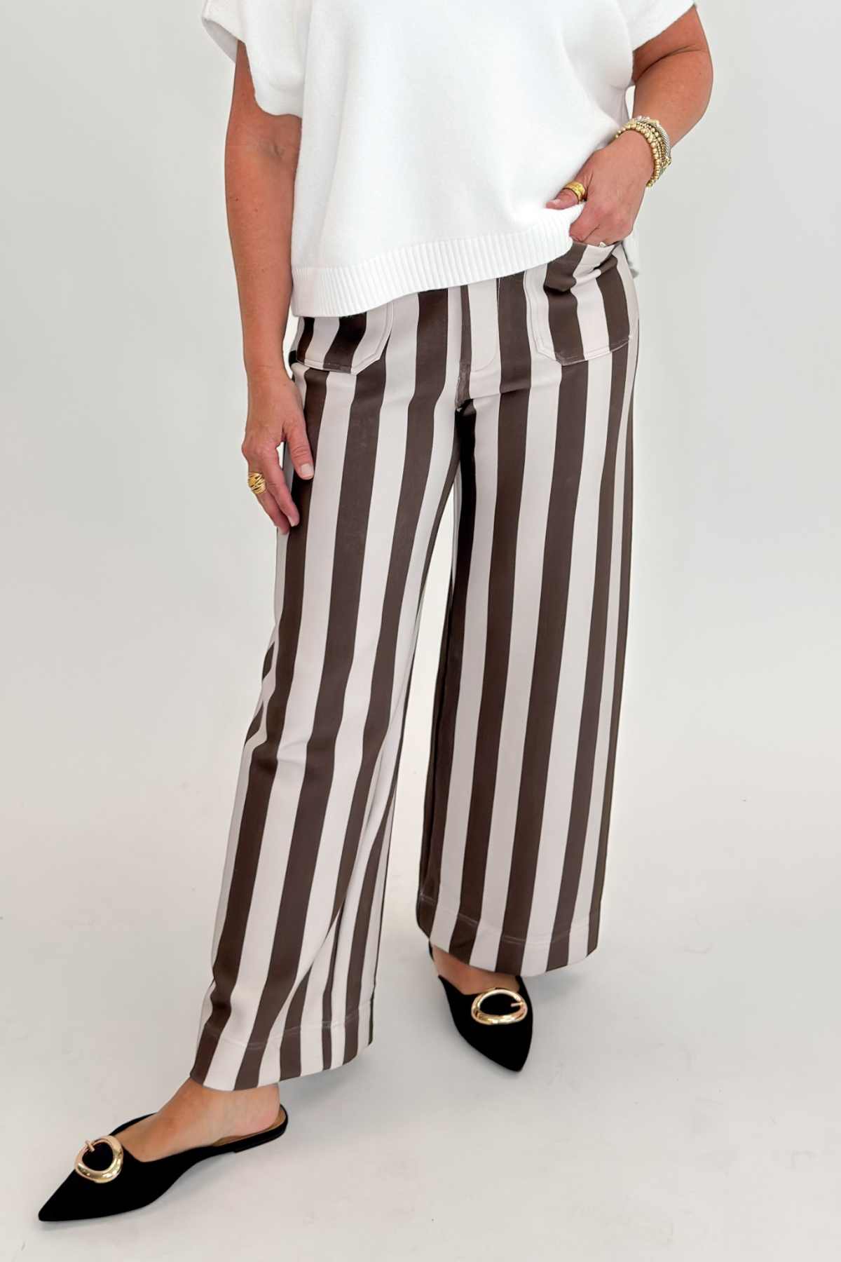 Front view of woman wearing Swagger Boutique’s sweater with Brown & Beige Striped Pants by Entro against white studio background.