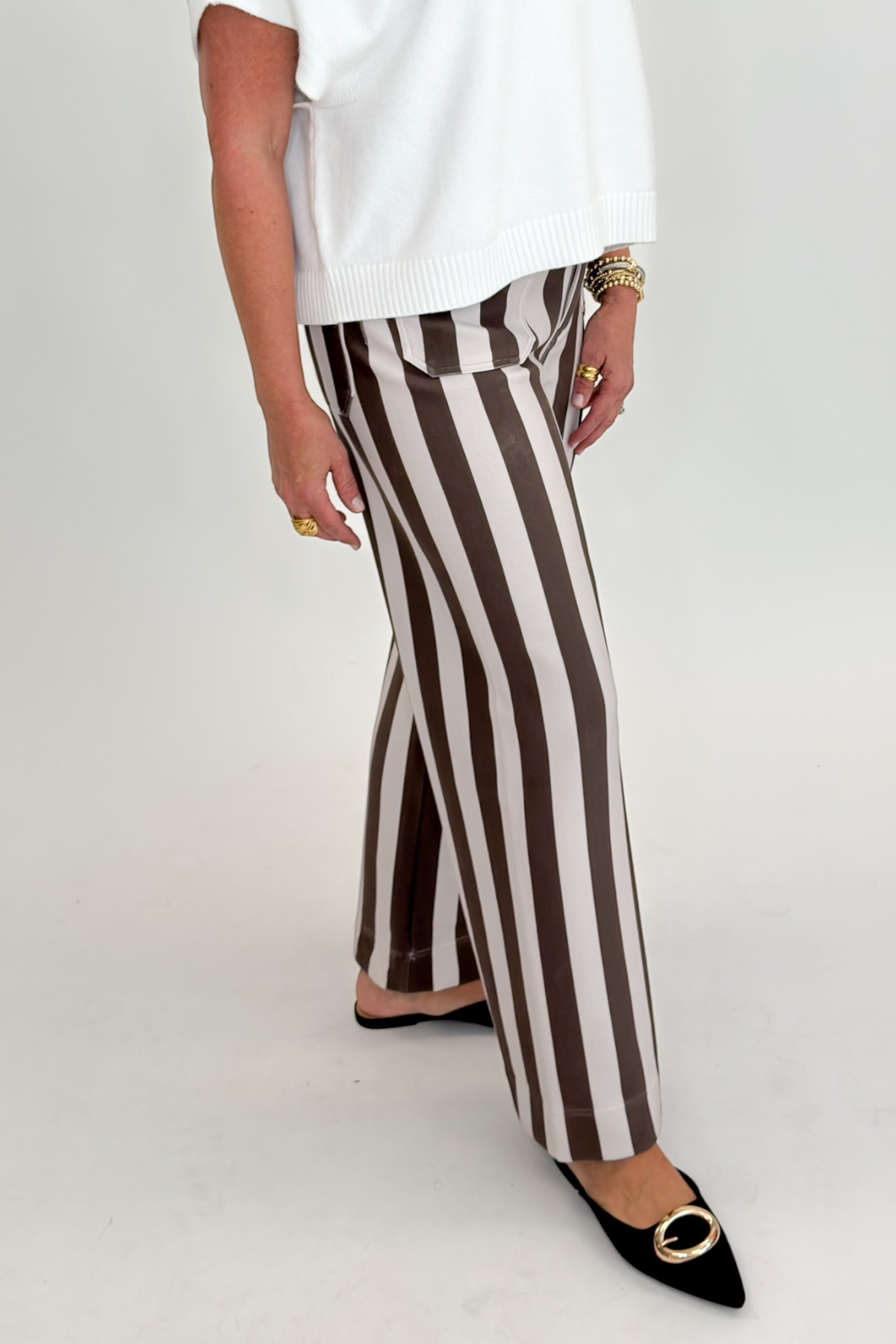 Side view of woman wearing Swagger Boutique’s sweater with Brown & Beige Striped Pants by Entro against white studio background.
